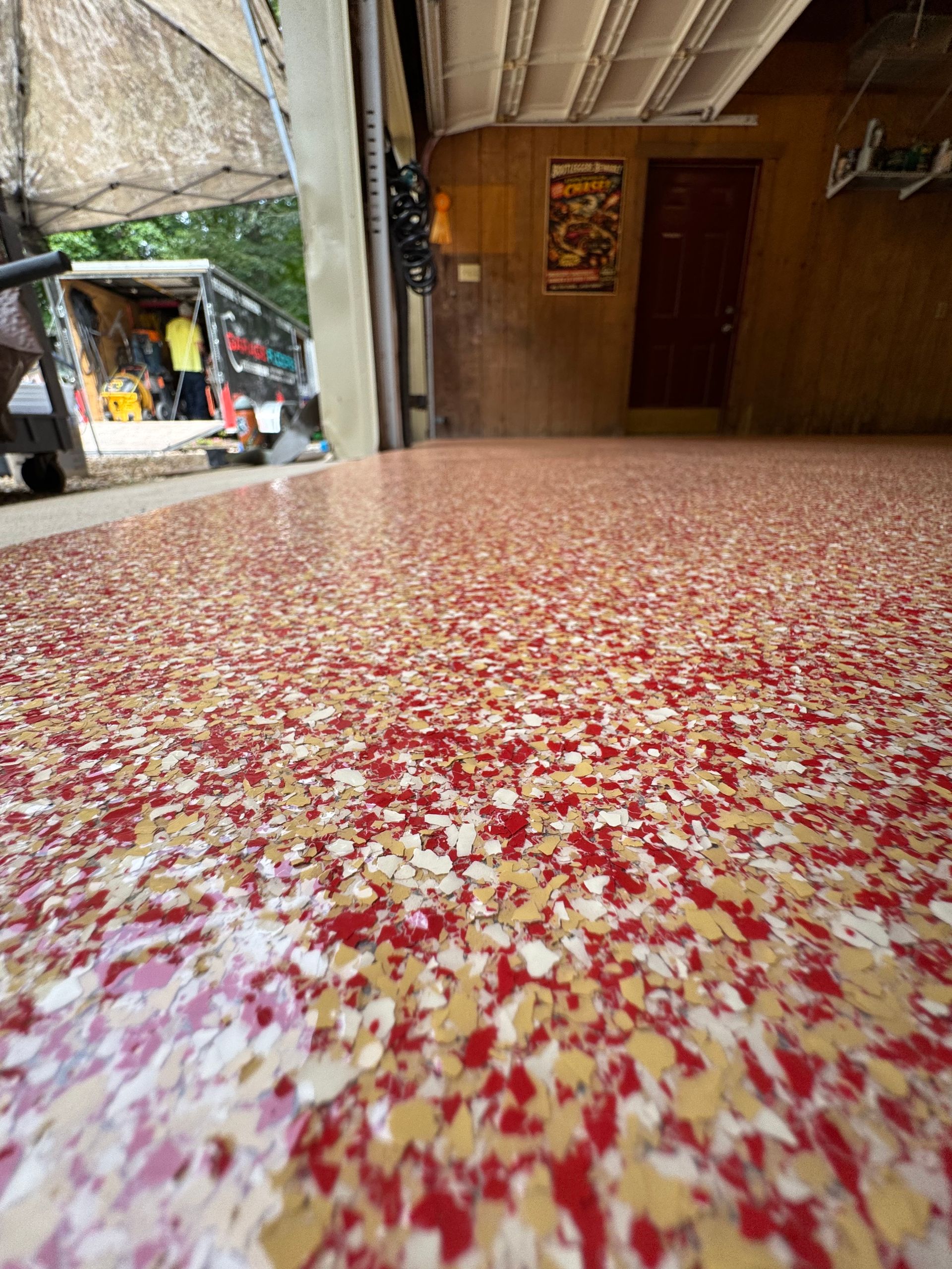 Red-speckled countertop in a rustic open-air kitchen with wooden walls and a small outdoor stall nearby