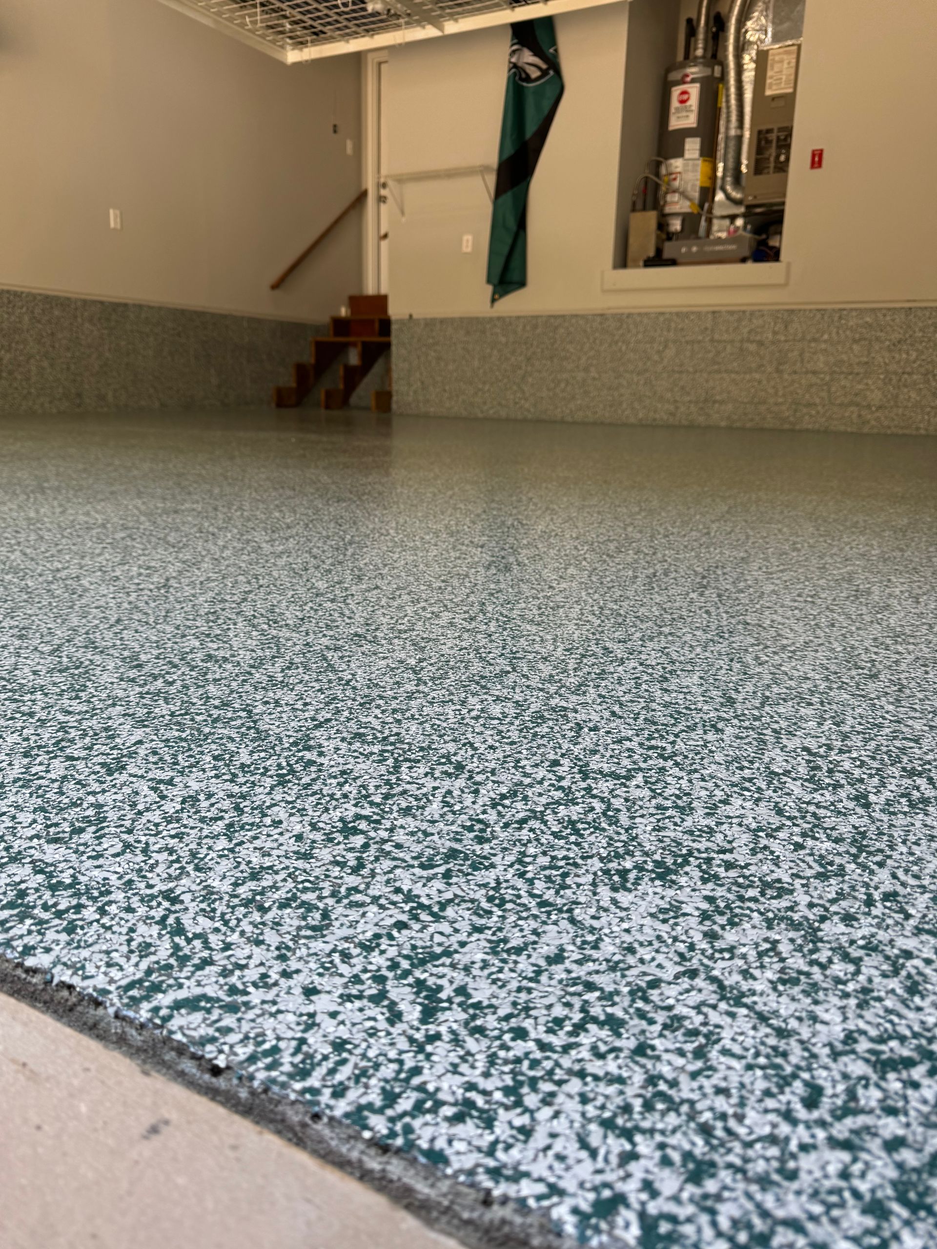Speckled blue-gray epoxy floor in a basement room with stairs and a doorway in the background