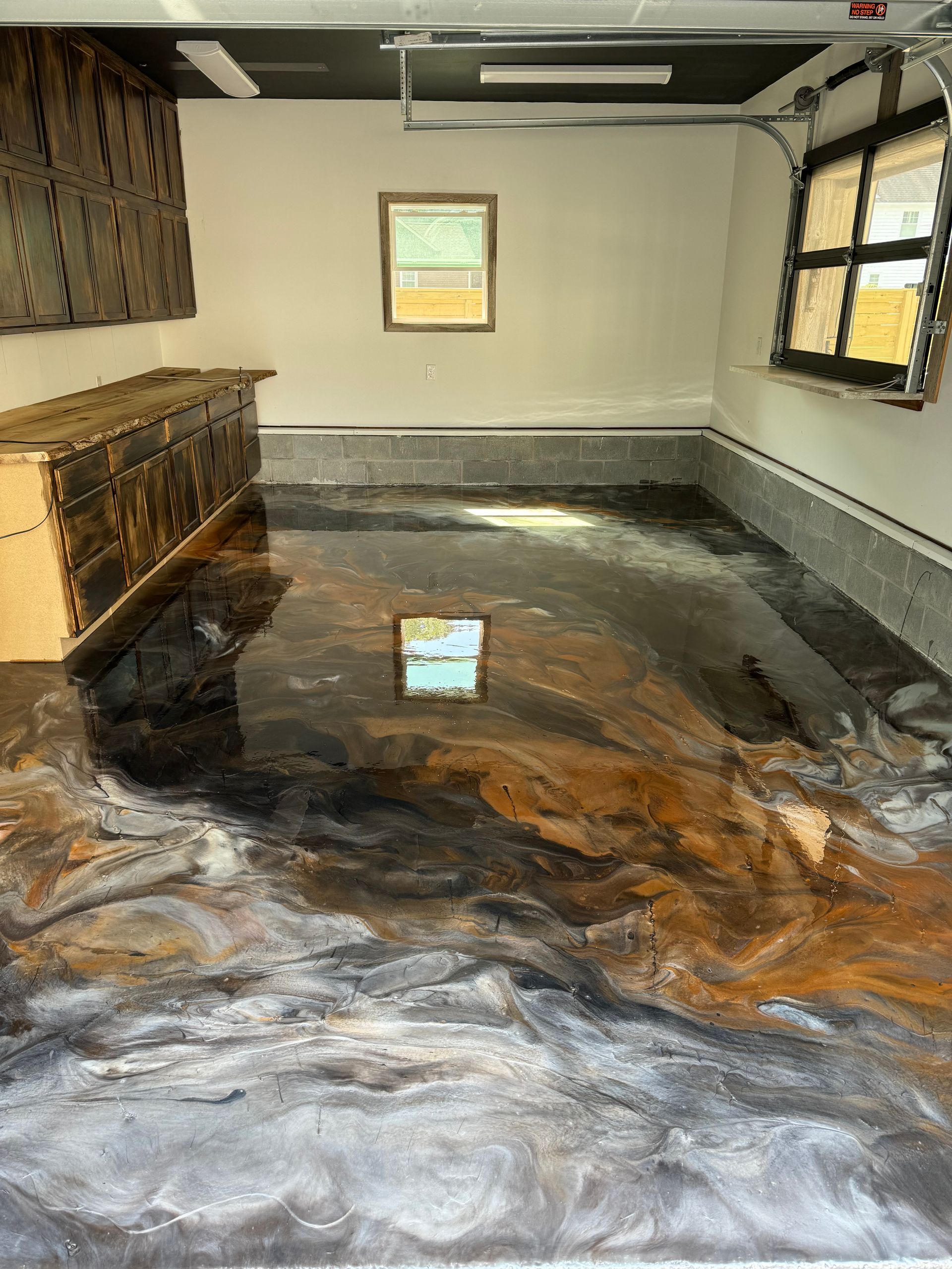 Flooded room with water covering the floor, reflecting windows and a wall-mounted cabinet.