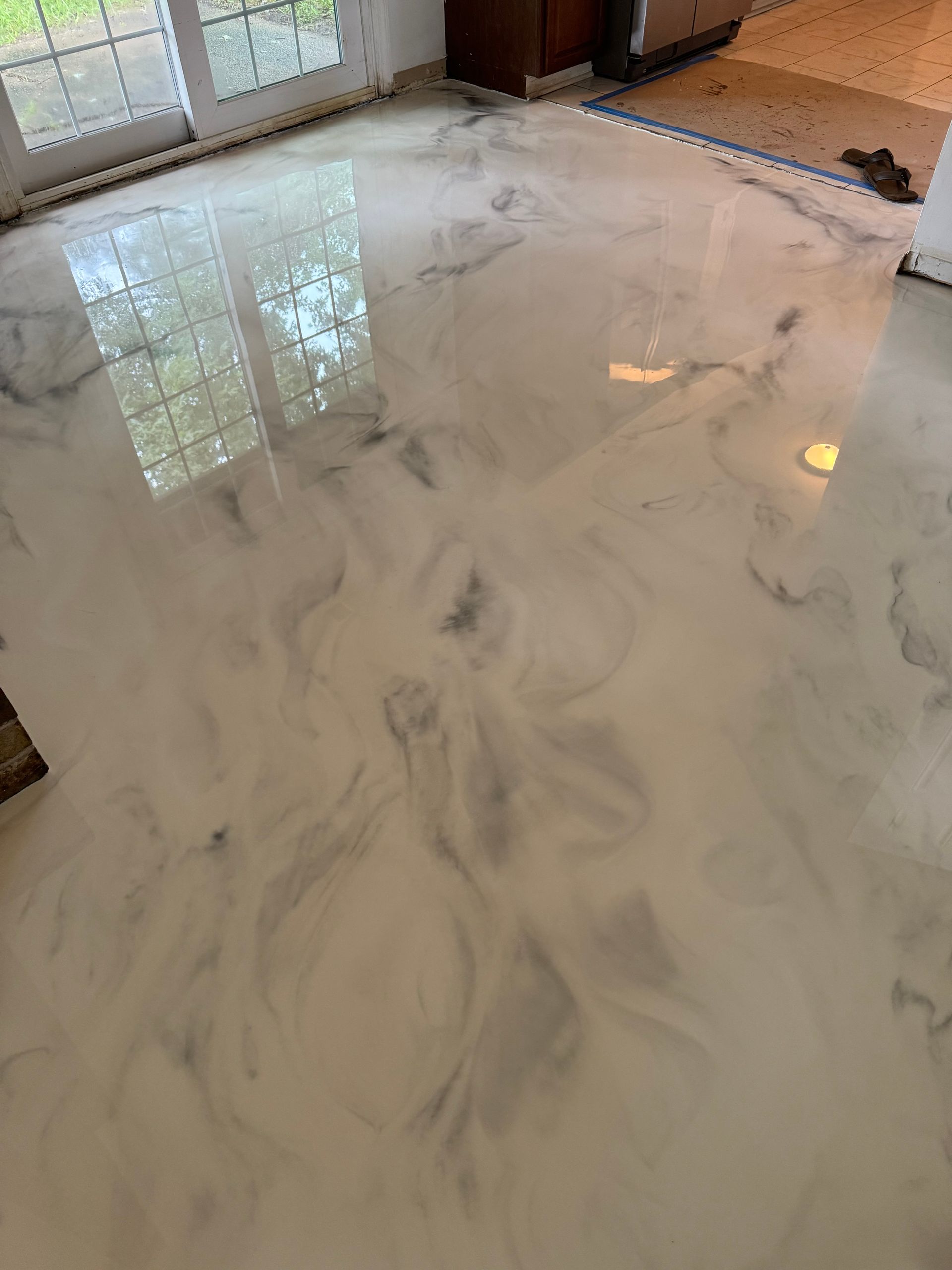 Polished white marble floor with gray veining in a bright room near glass doors
