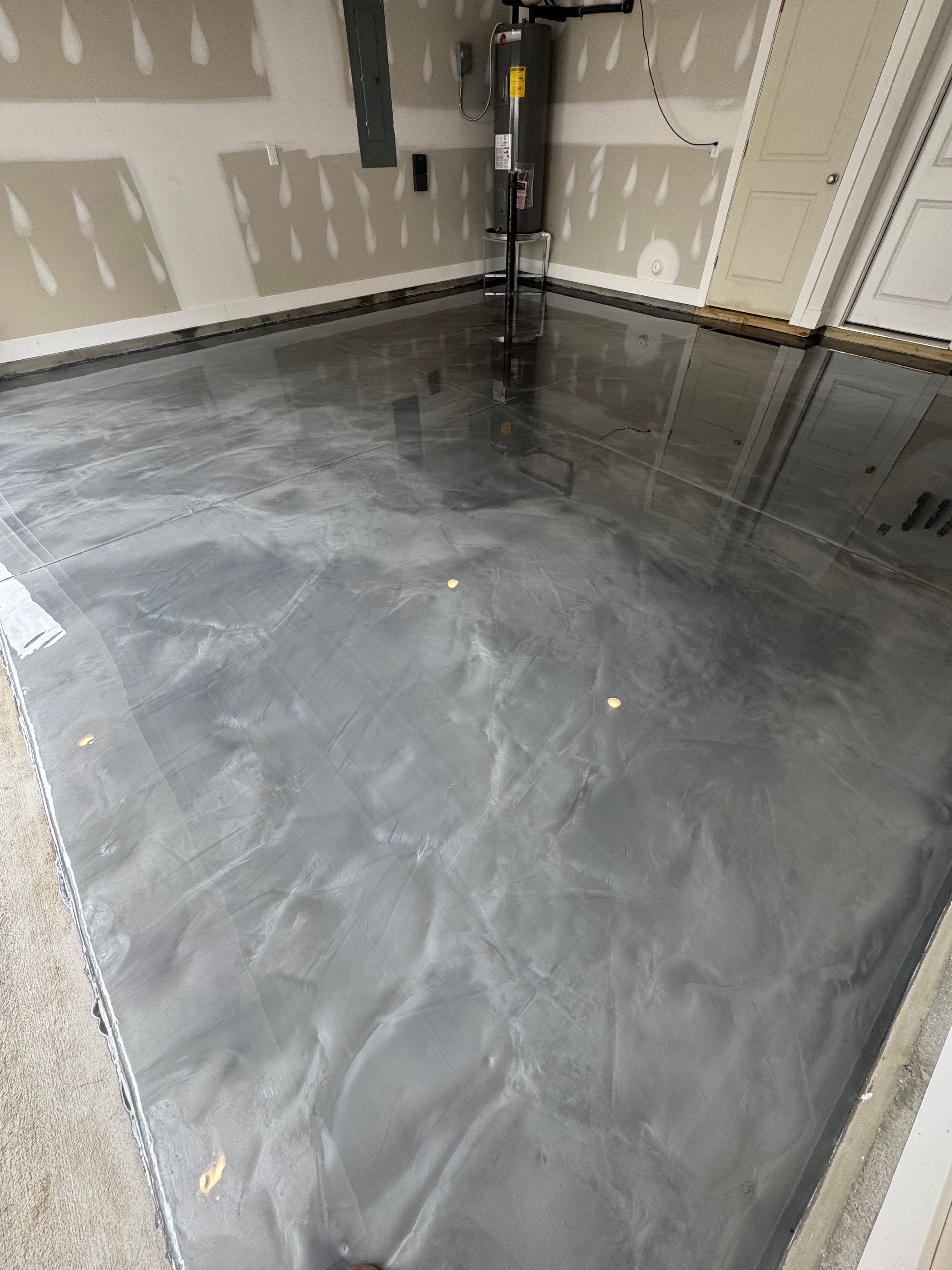 Empty garage with a freshly coated gray concrete floor and unfinished drywall walls