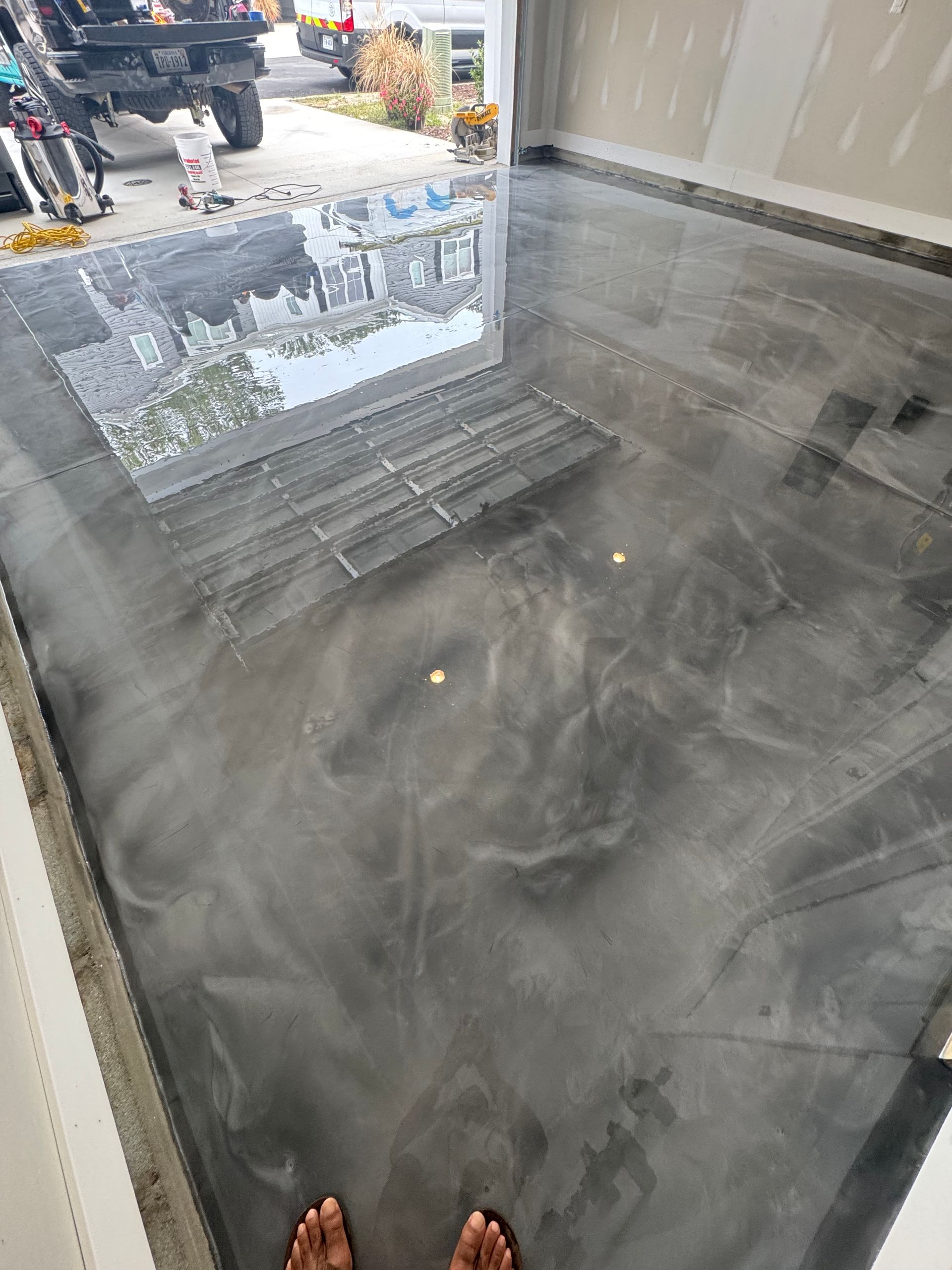 Smoky gray tiled floor at a storefront entrance with a small step and street reflected in the glass door.