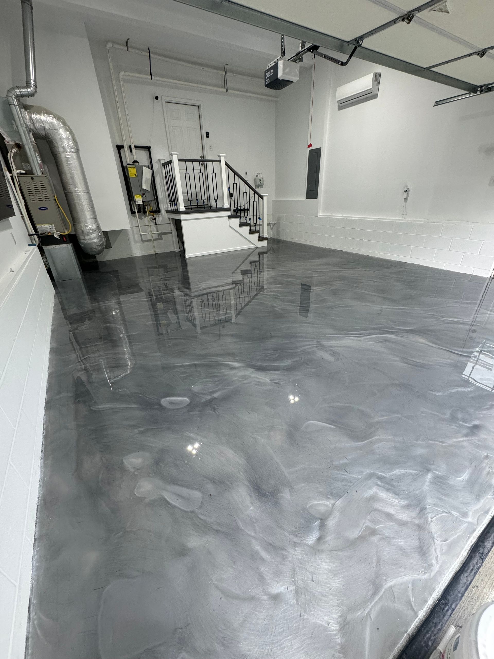 Empty industrial room with glossy gray floor, white walls, pipes, and equipment along the left side.