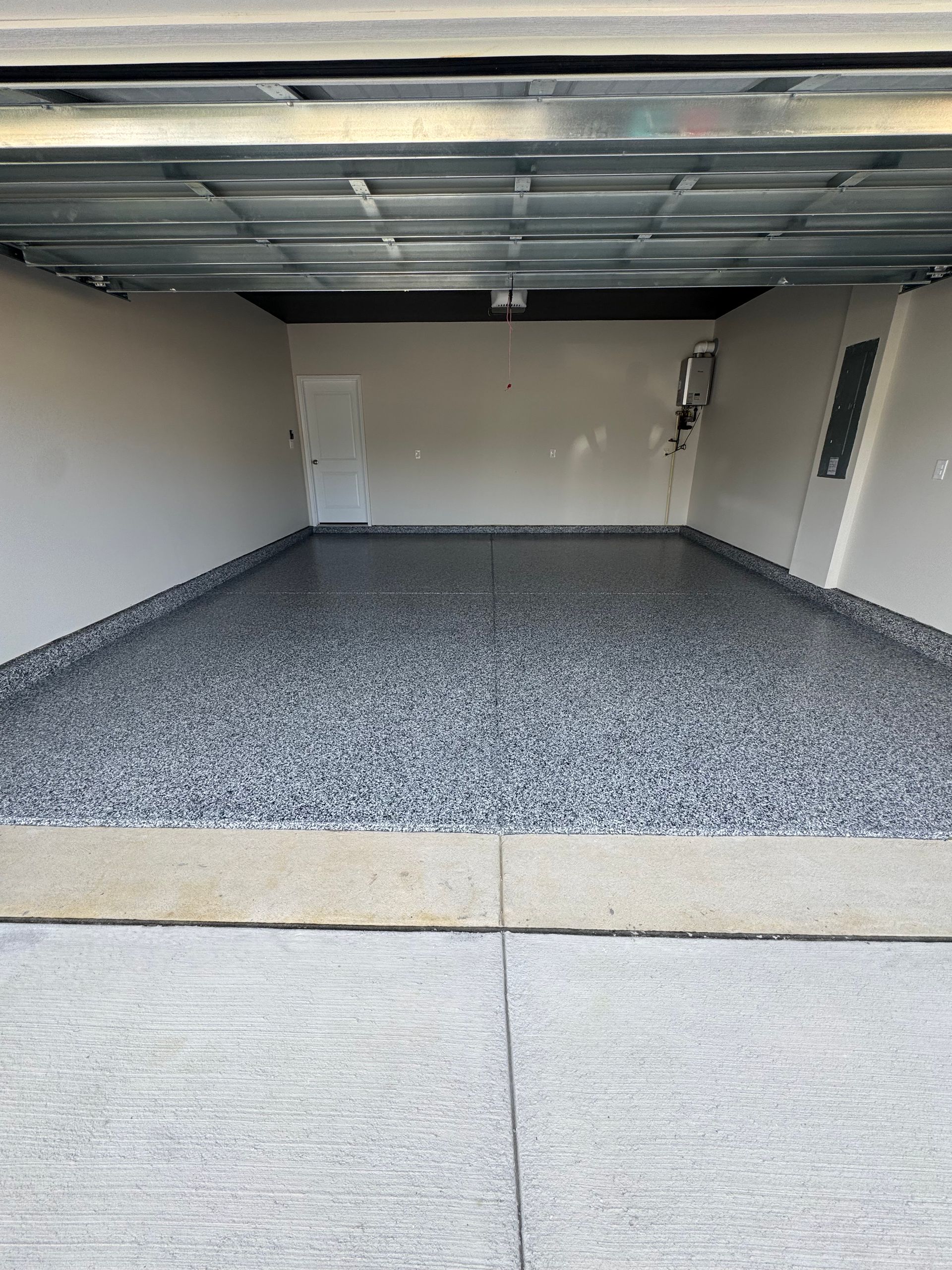 Empty garage with speckled epoxy floor and closed overhead door