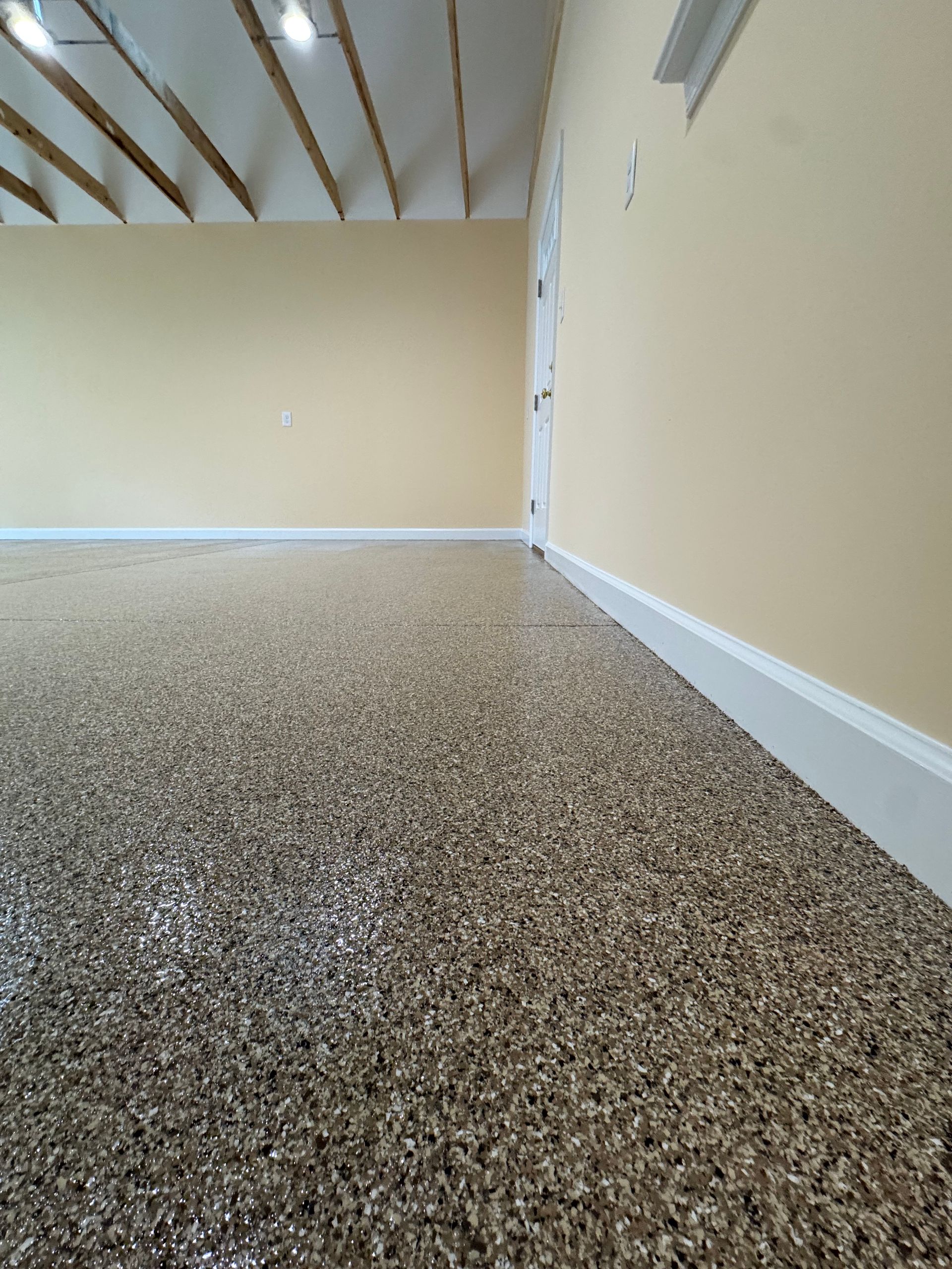 Empty beige room with speckled carpet and sloped wood-beam ceiling