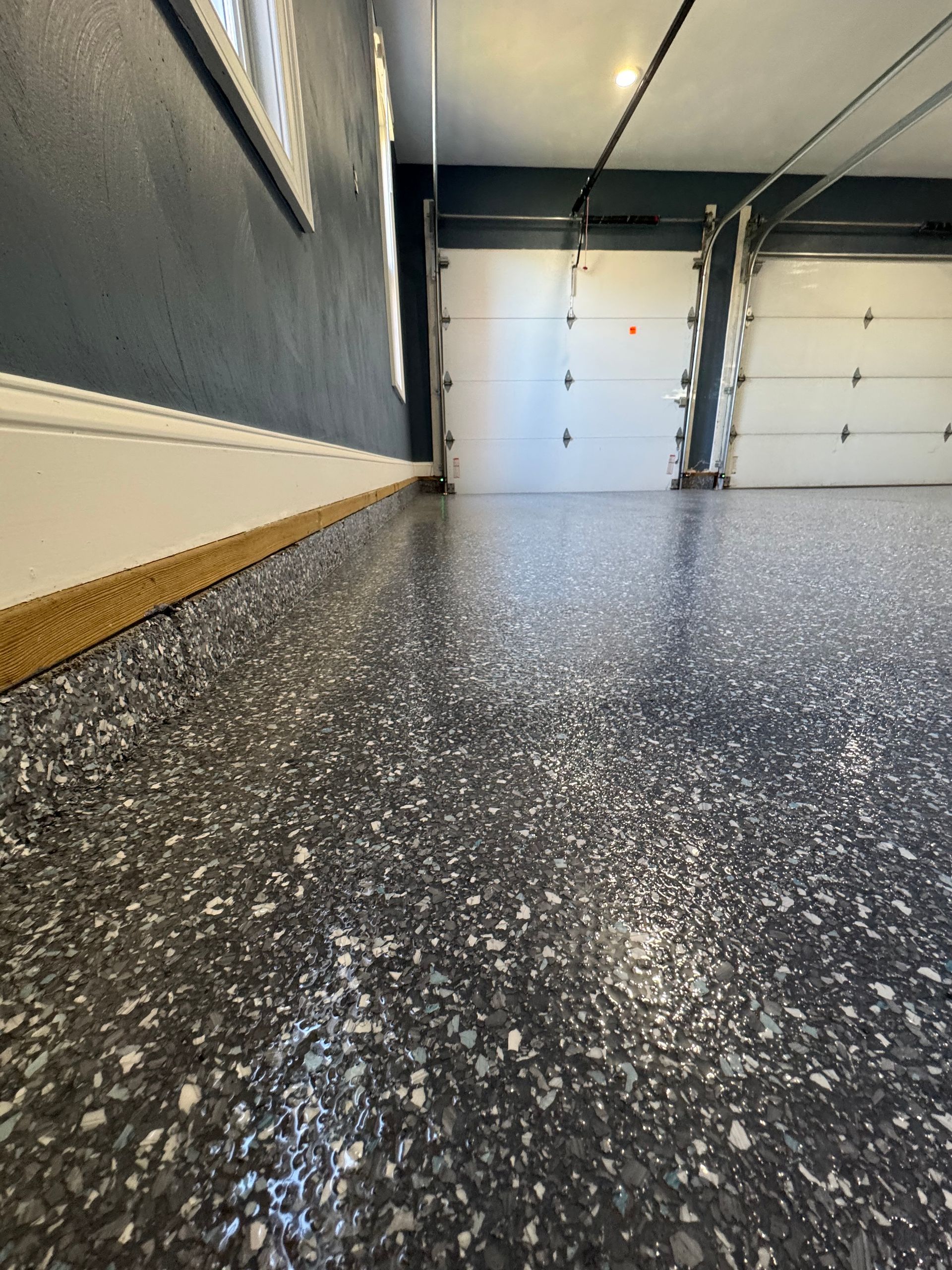 Garage interior with speckled epoxy floor and closed white garage door.