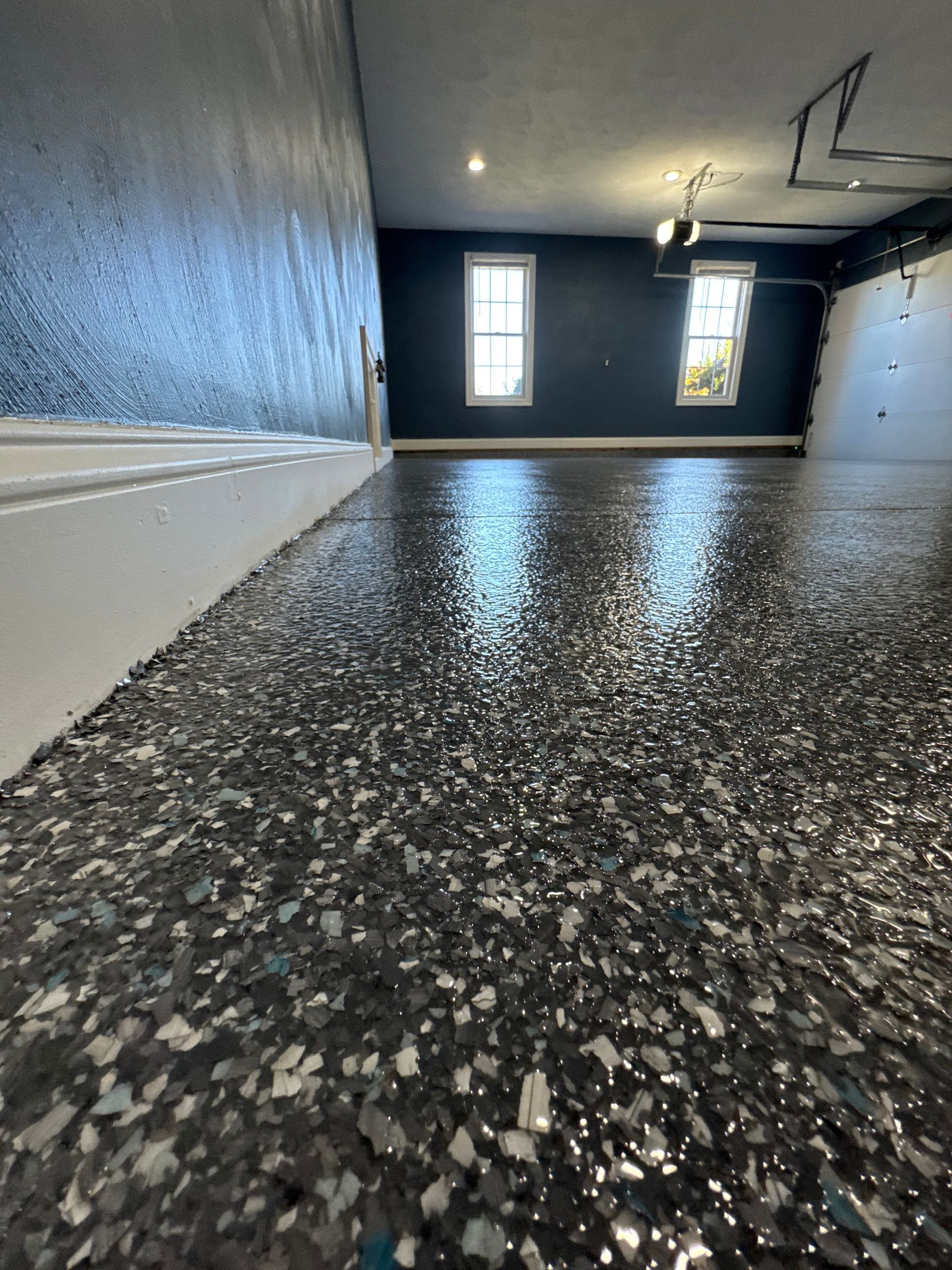 Empty garage with speckled epoxy floor and white walls, viewed from floor level.