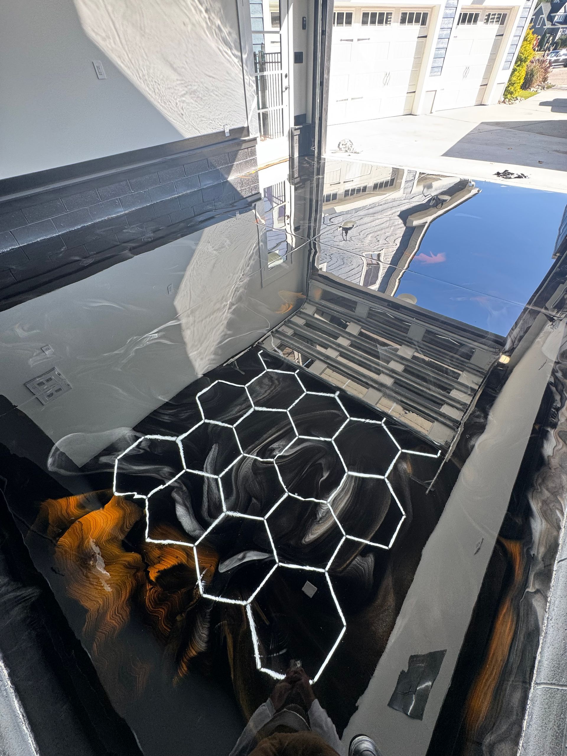 Cracked black glass with a honeycomb-patterned insert, reflecting buildings and sky.