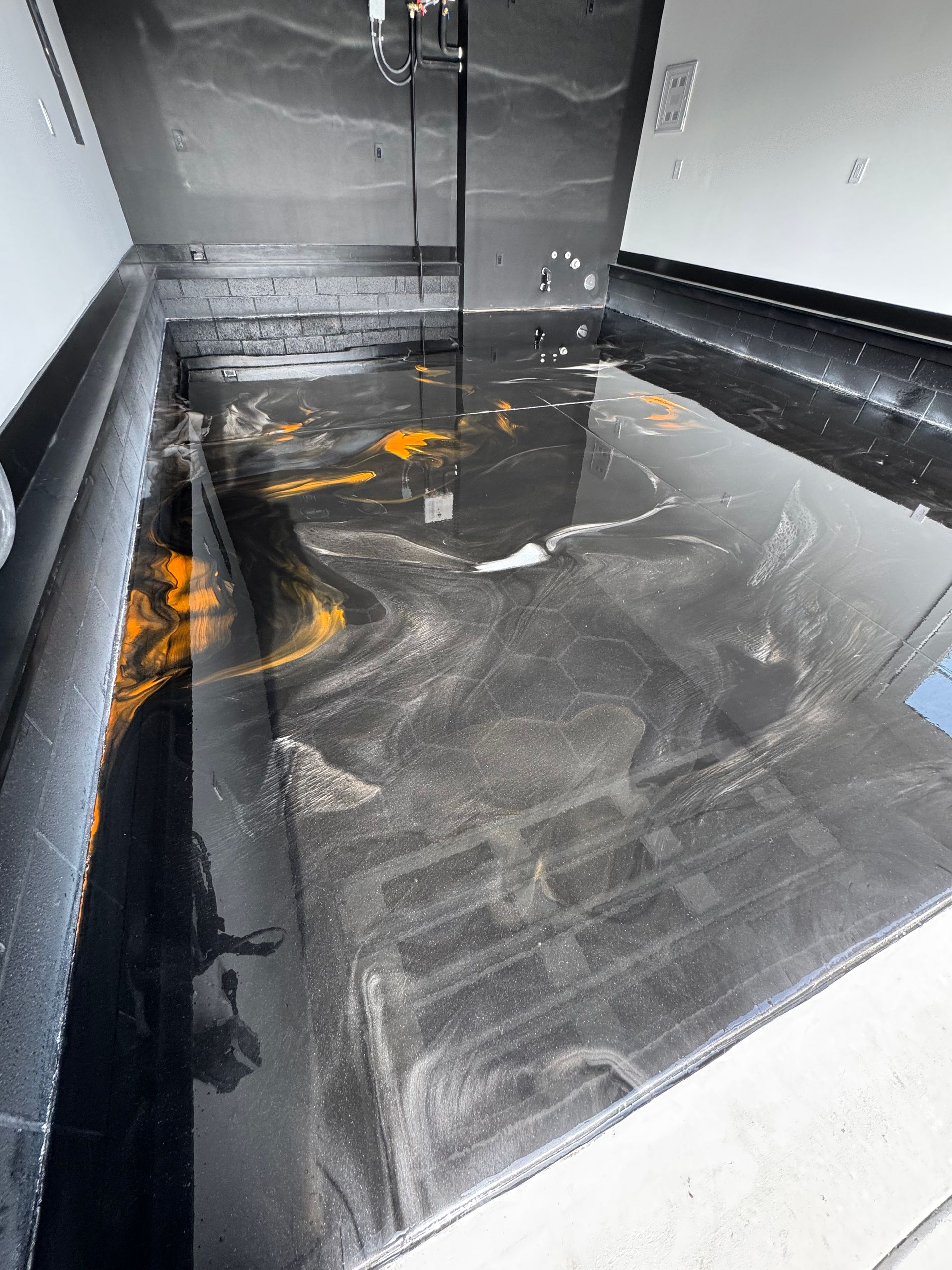 Gray utility sink with standing water, black liner, and scattered orange debris in a corner.