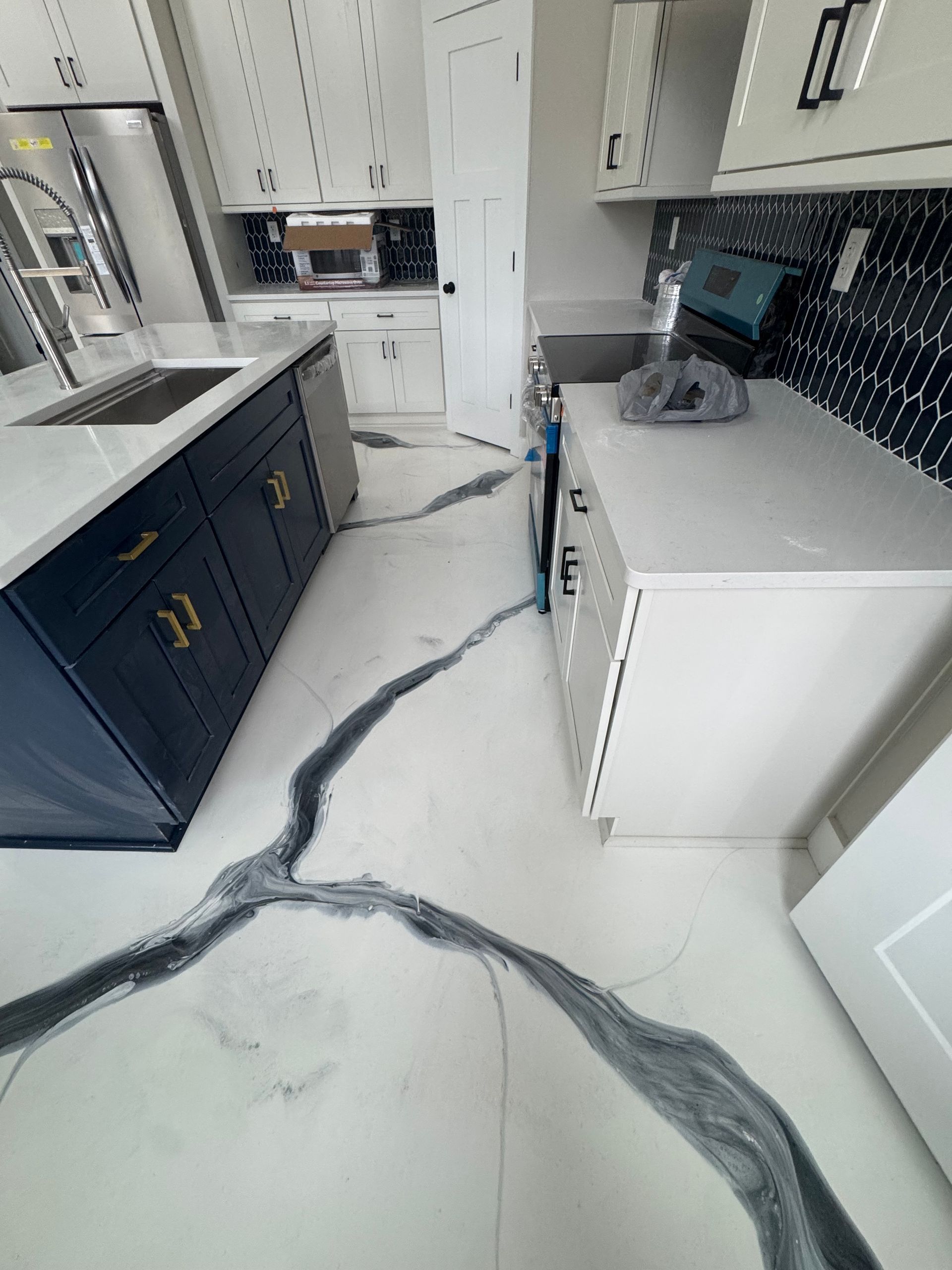 Modern kitchen with dark cabinets, white island, and long gray protective floor covering before installation