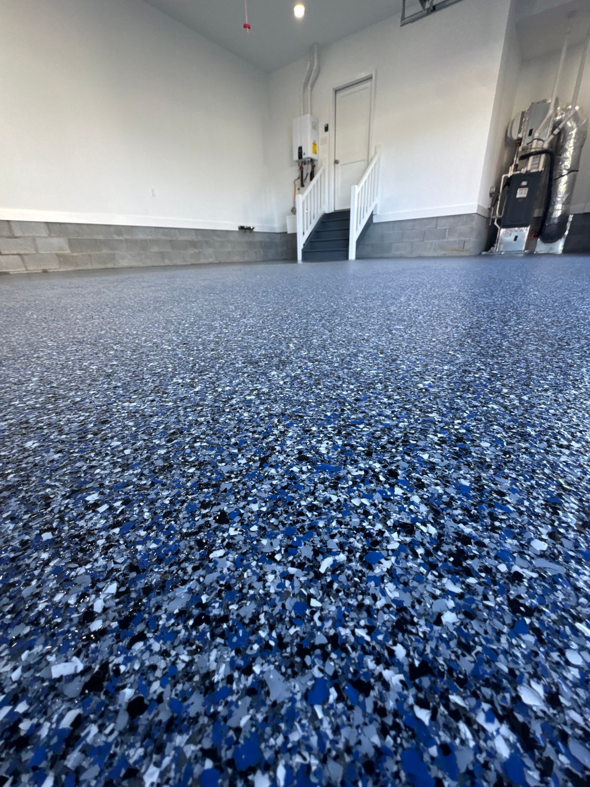 Blue-speckled epoxy garage floor with a gray wall and door in the background