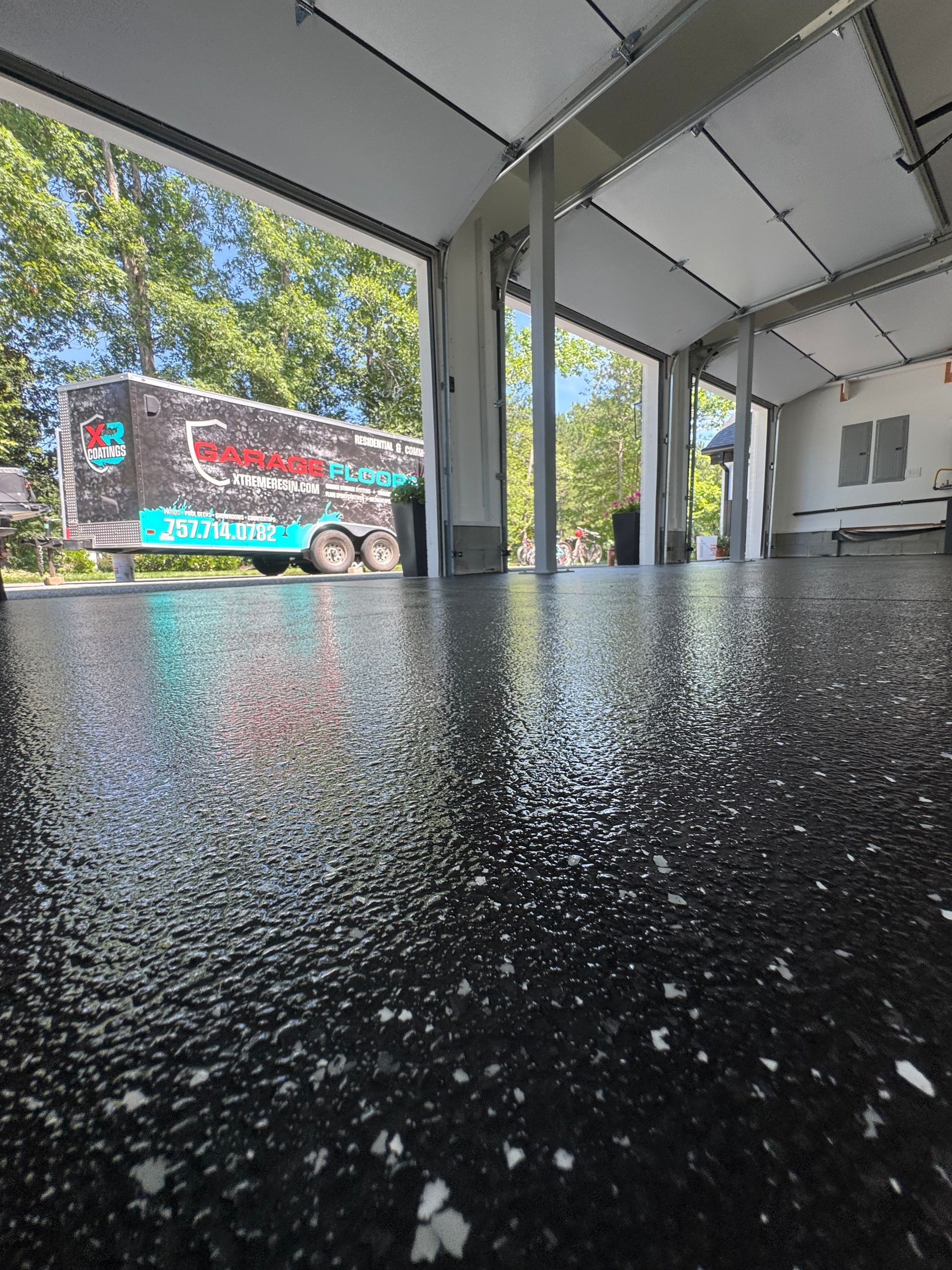 Low-angle view of a covered patio with a speckled black table and a colorful bus parked outside.