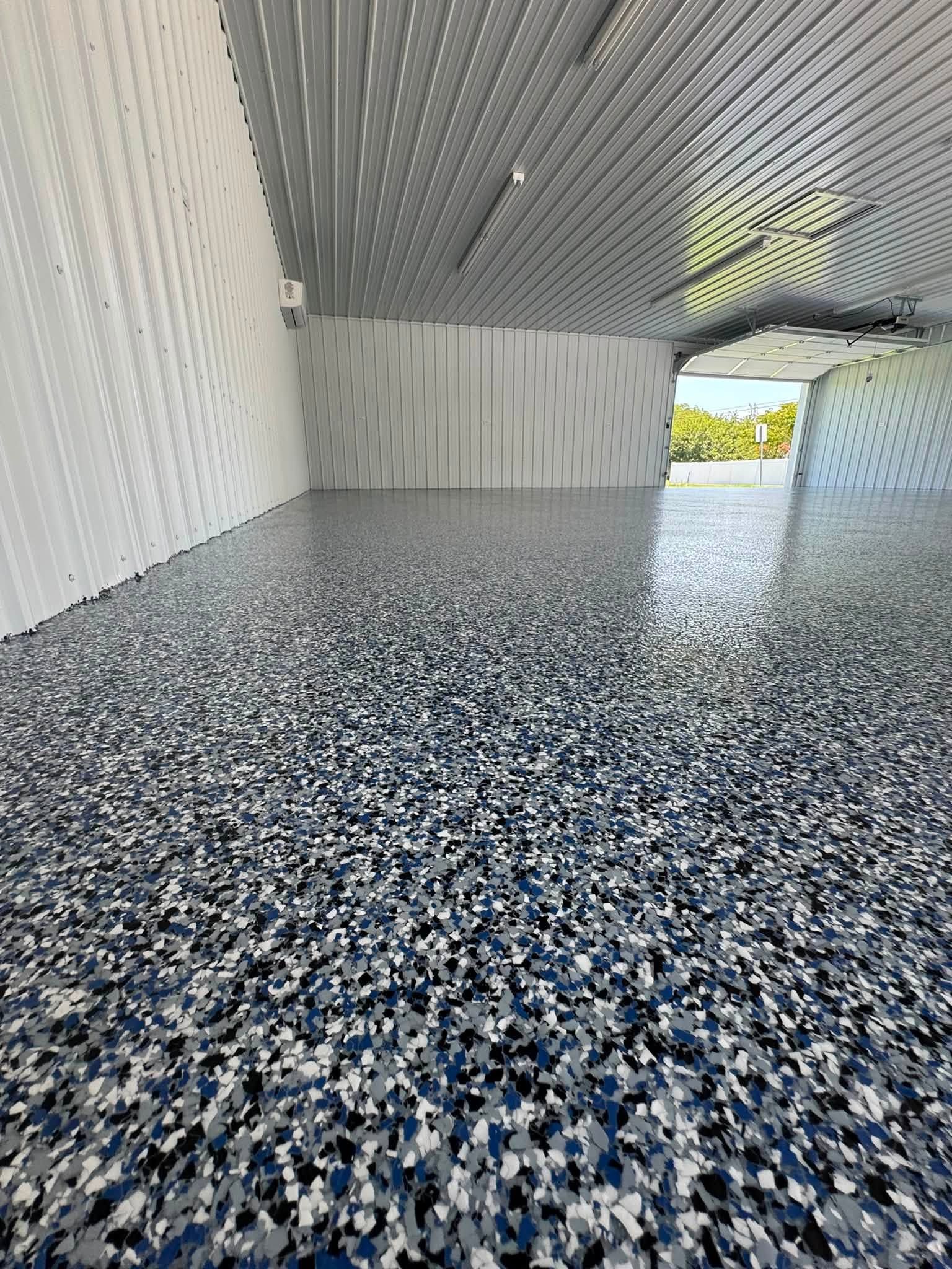 Empty covered walkway with speckled epoxy floor and corrugated metal walls and ceiling.