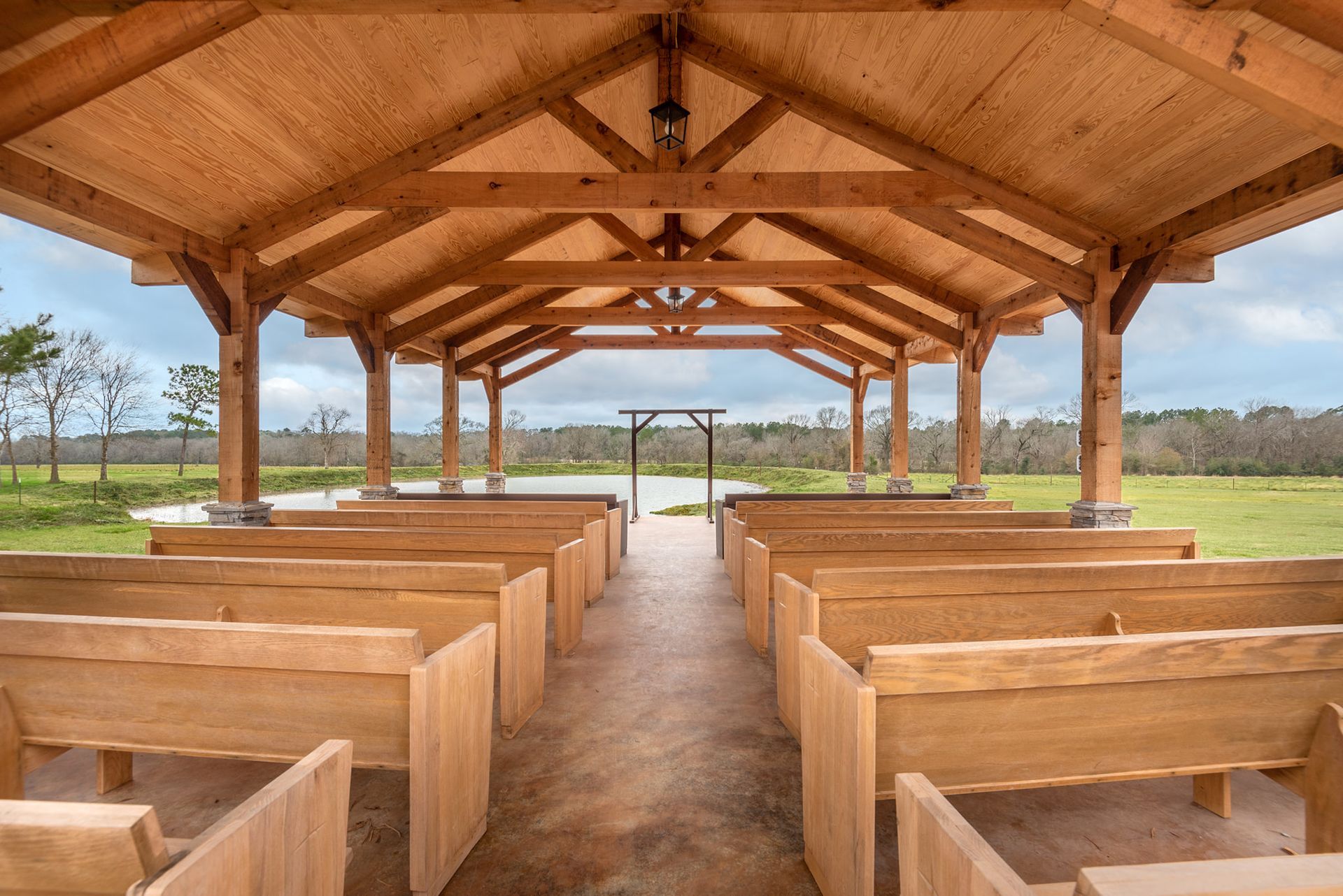 Wooden pavilion with rows of church pews overlooking a grassy field