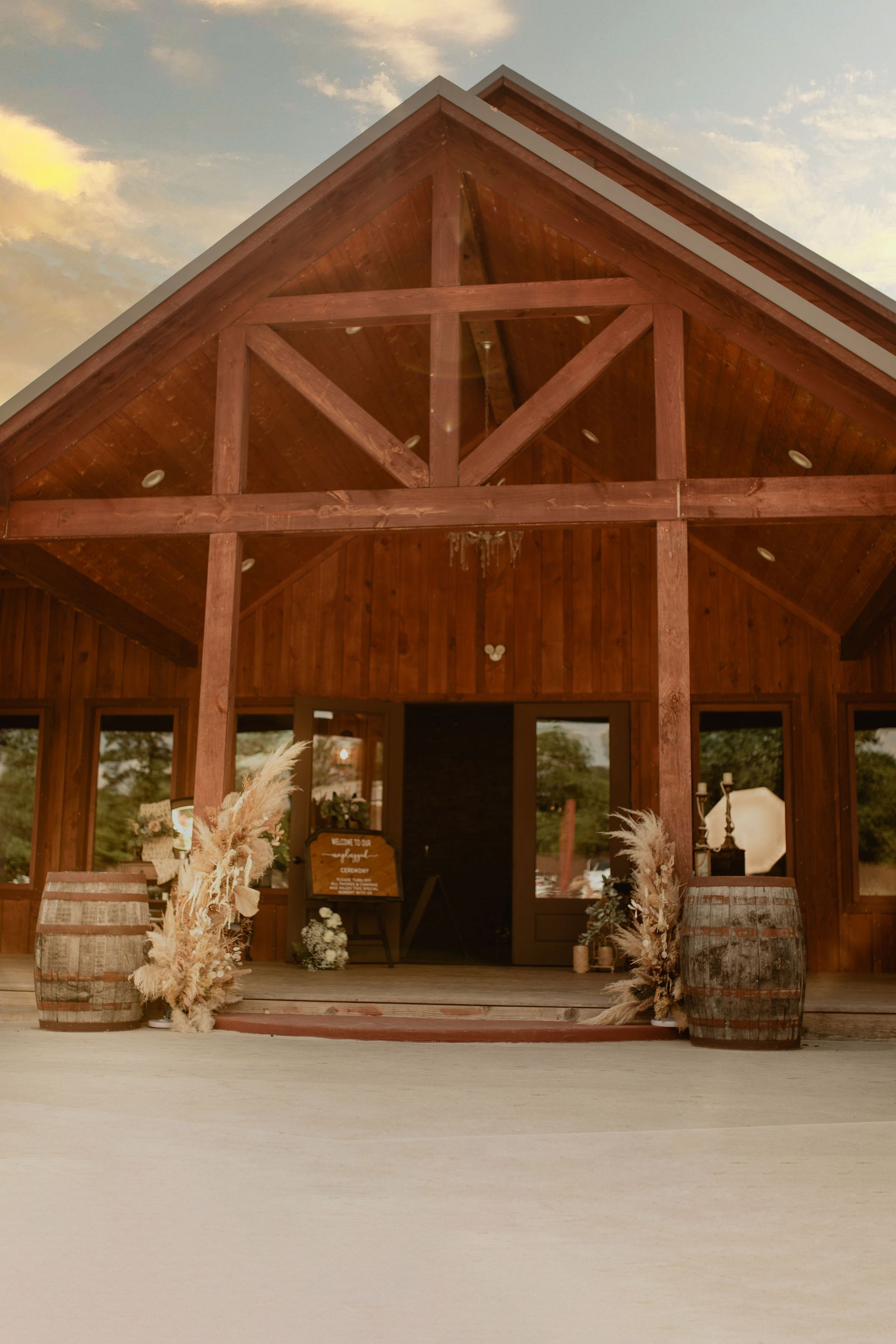Rustic wooden chapel entrance with floral arrangements on either side and an open doorway at sunset