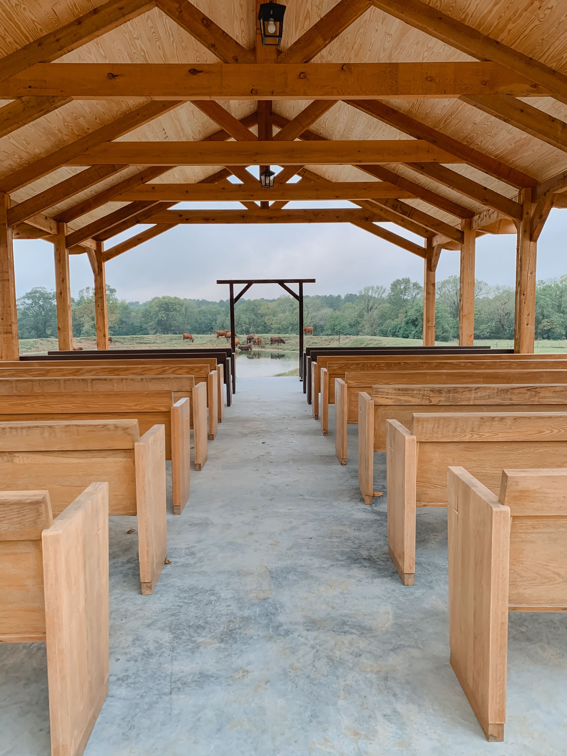 Empty wooden chapel with rows of pews and open view through the front