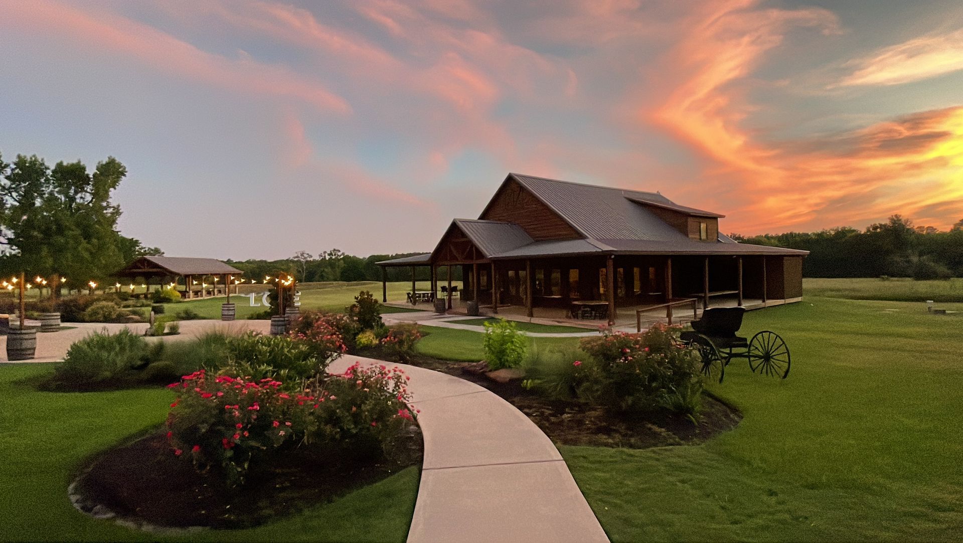 Curved garden path leads to a rustic pavilion at sunset, with flower beds and a colorful sky
