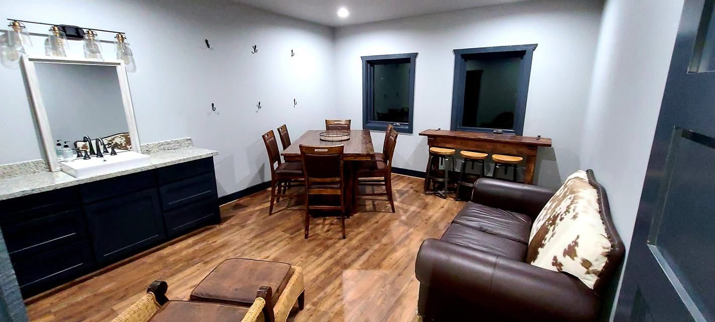 Living room with brown leather sofa, dining table, vanity, and hardwood floors