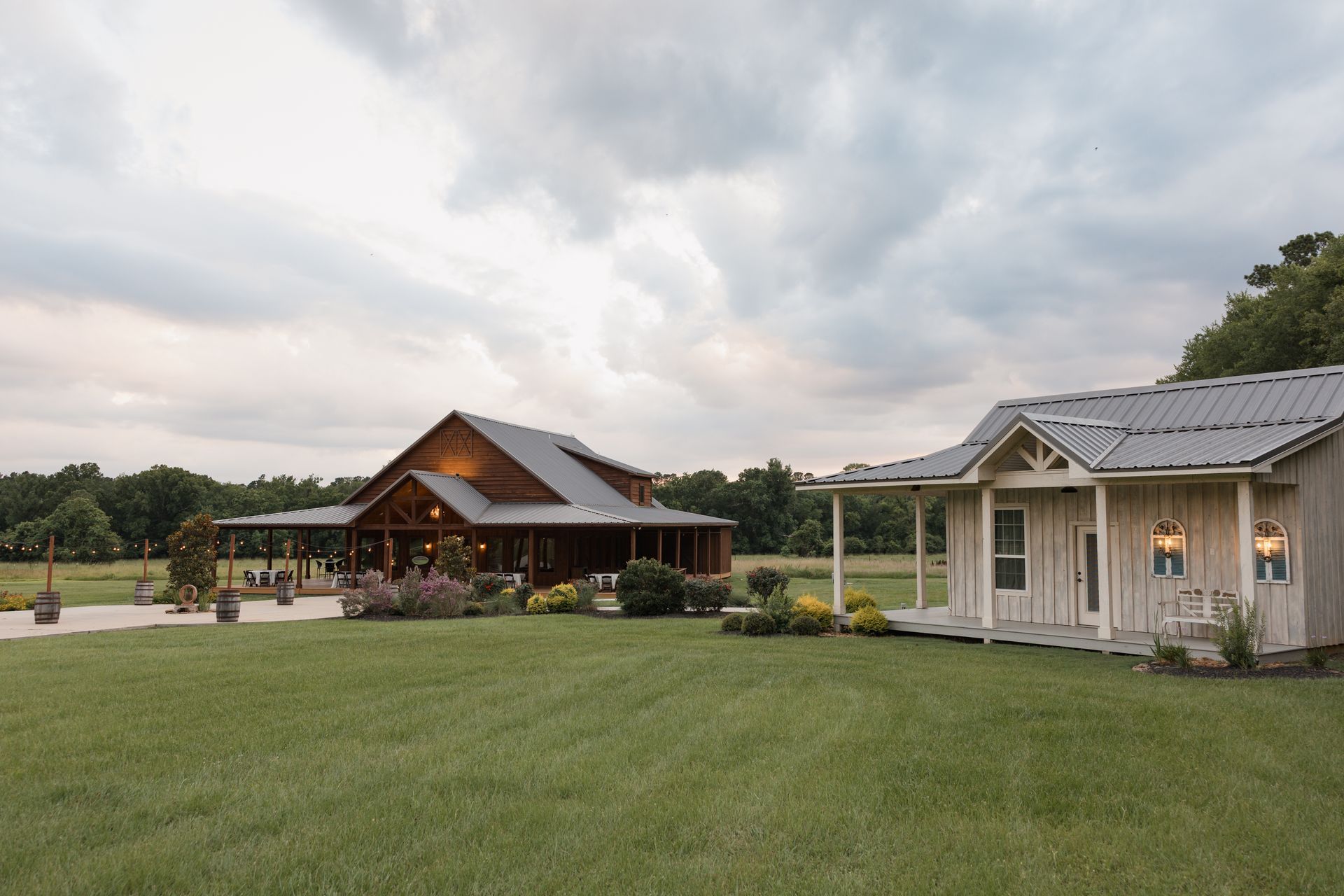 Two rustic cabins with metal roofs on a grassy property under a cloudy sky