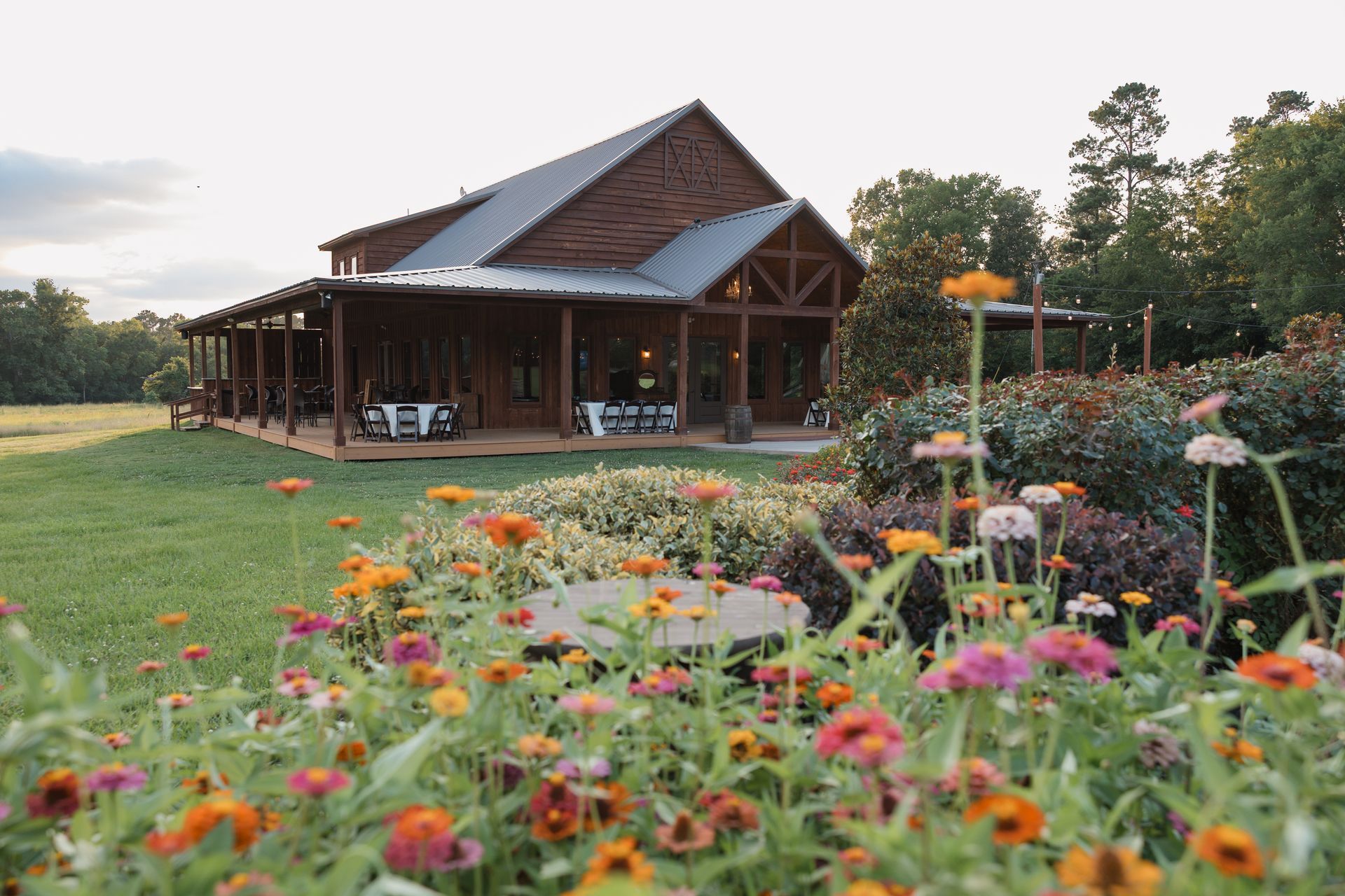 Rustic wooden cabin by a flower-filled garden under a cloudy sky