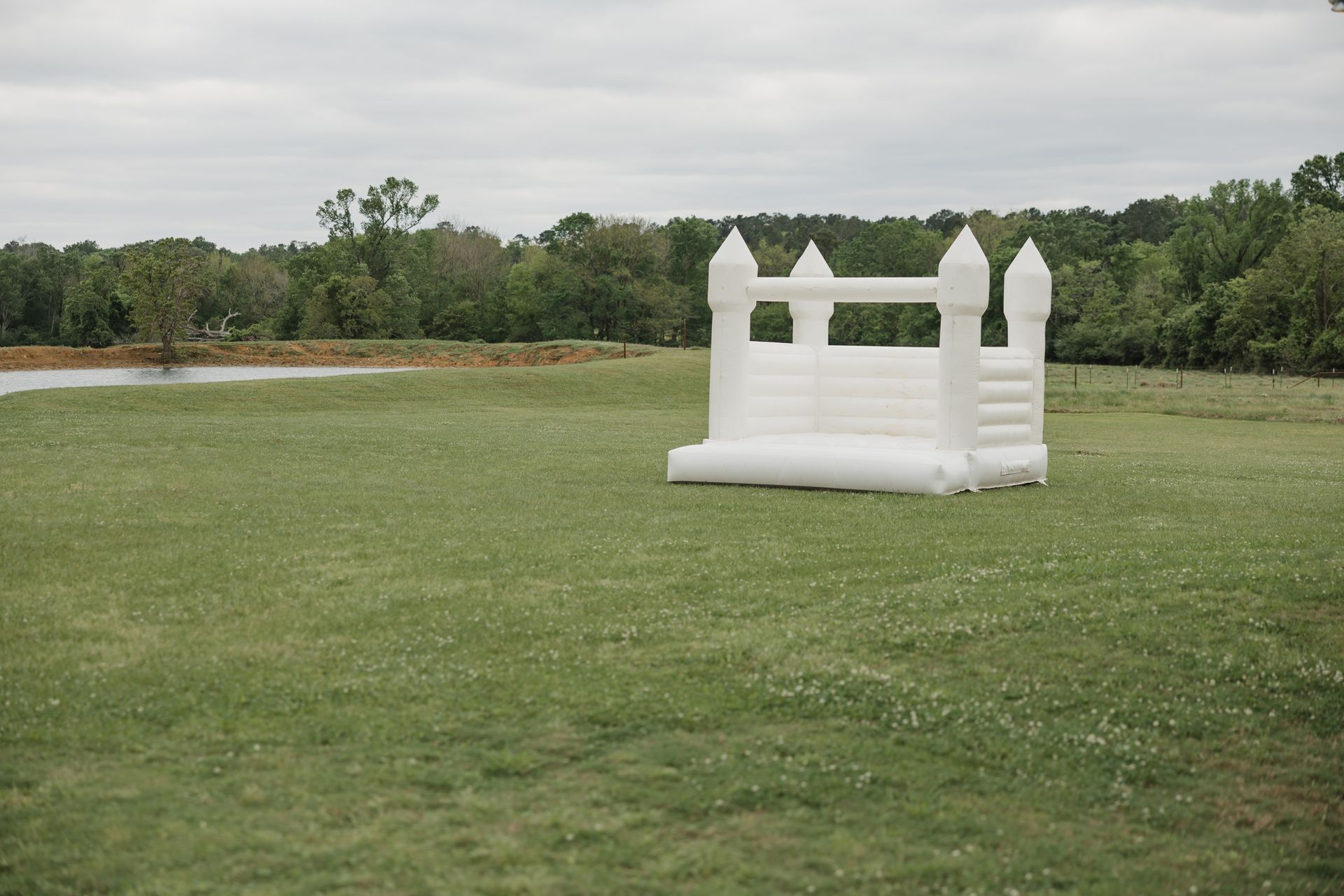 White inflatable bounce house on a grassy field under a cloudy sky
