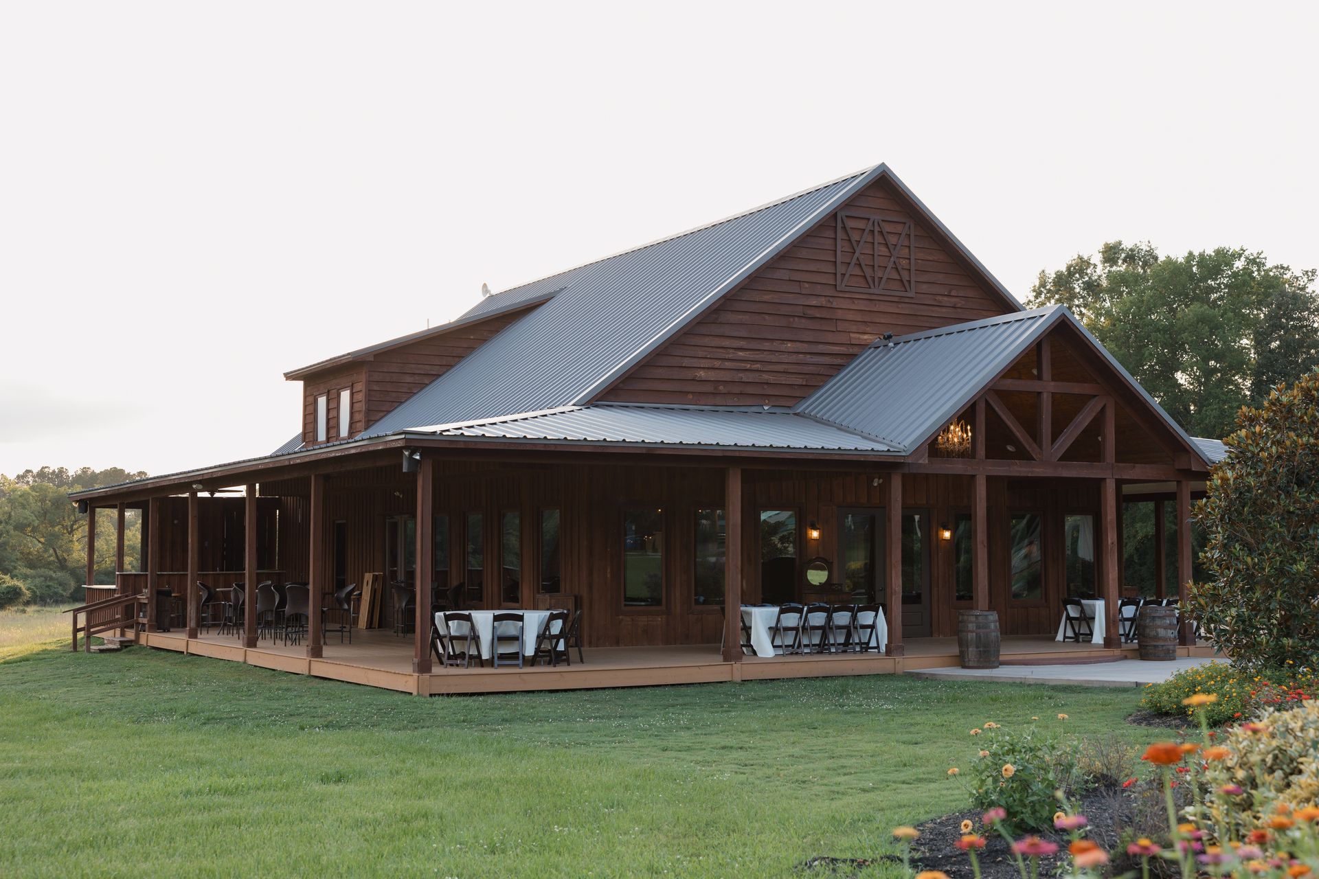 Rustic wooden house with a metal roof, covered porch, and lawn in a rural setting