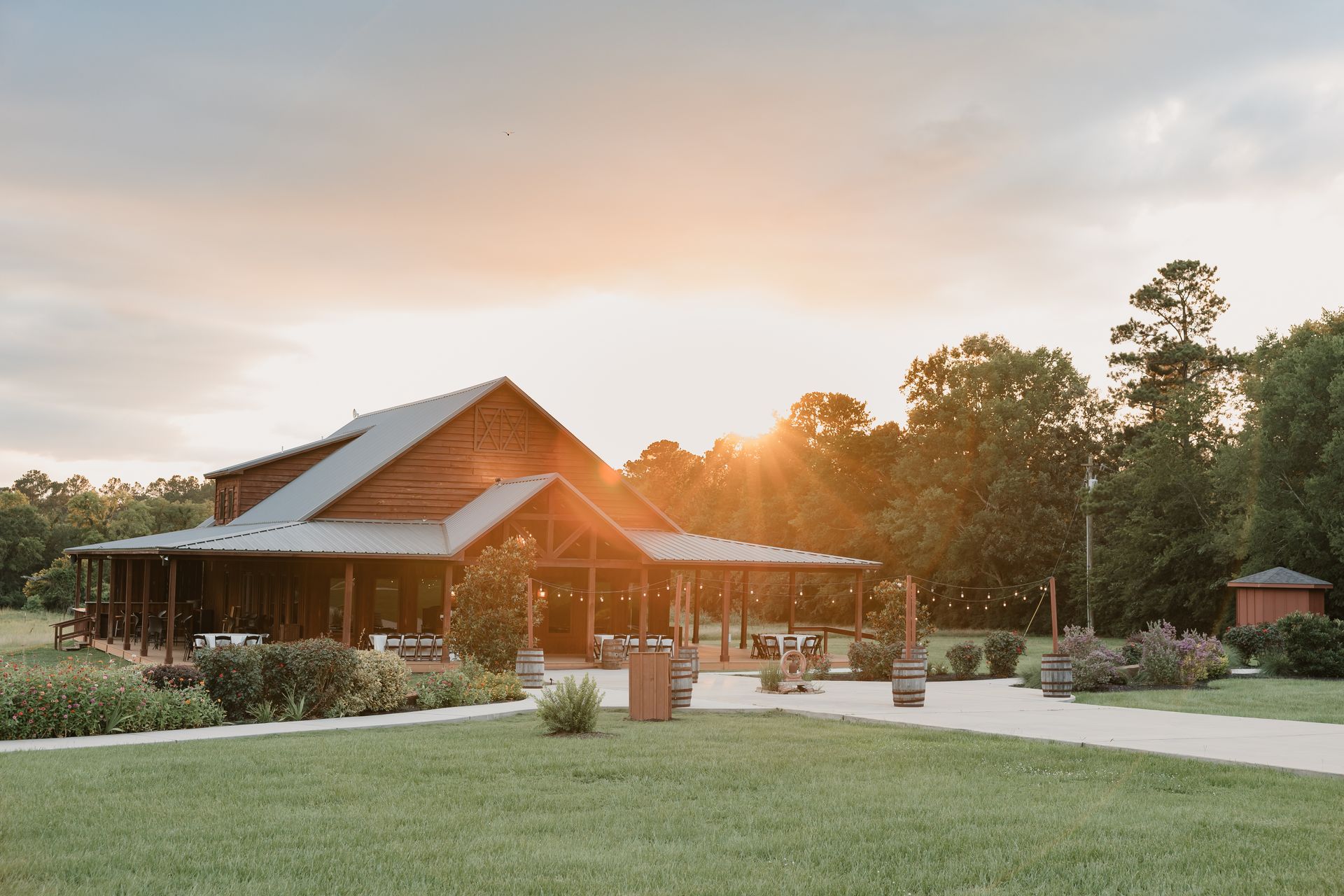Rustic lodge at sunset with a green lawn, paved path, and trees in the background