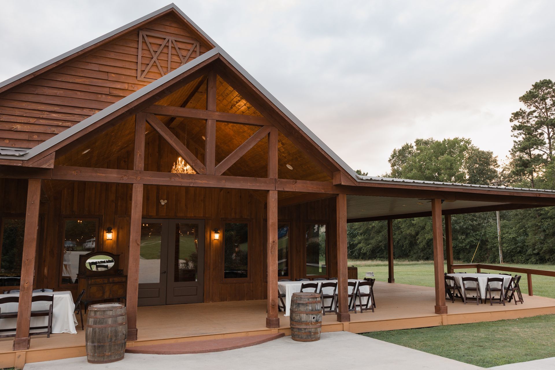 Rustic wooden lodge with a covered porch, stone pillars, and outdoor seating at dusk