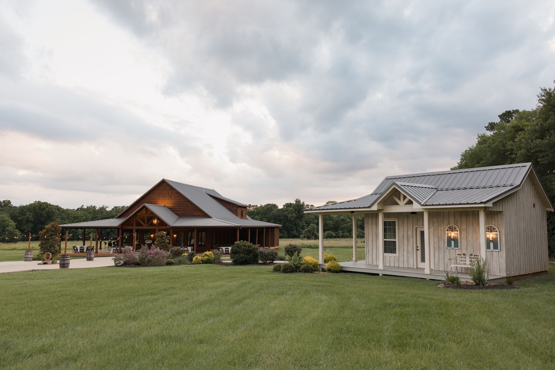 Wide grassy yard with a cabin and a small shed under cloudy skies