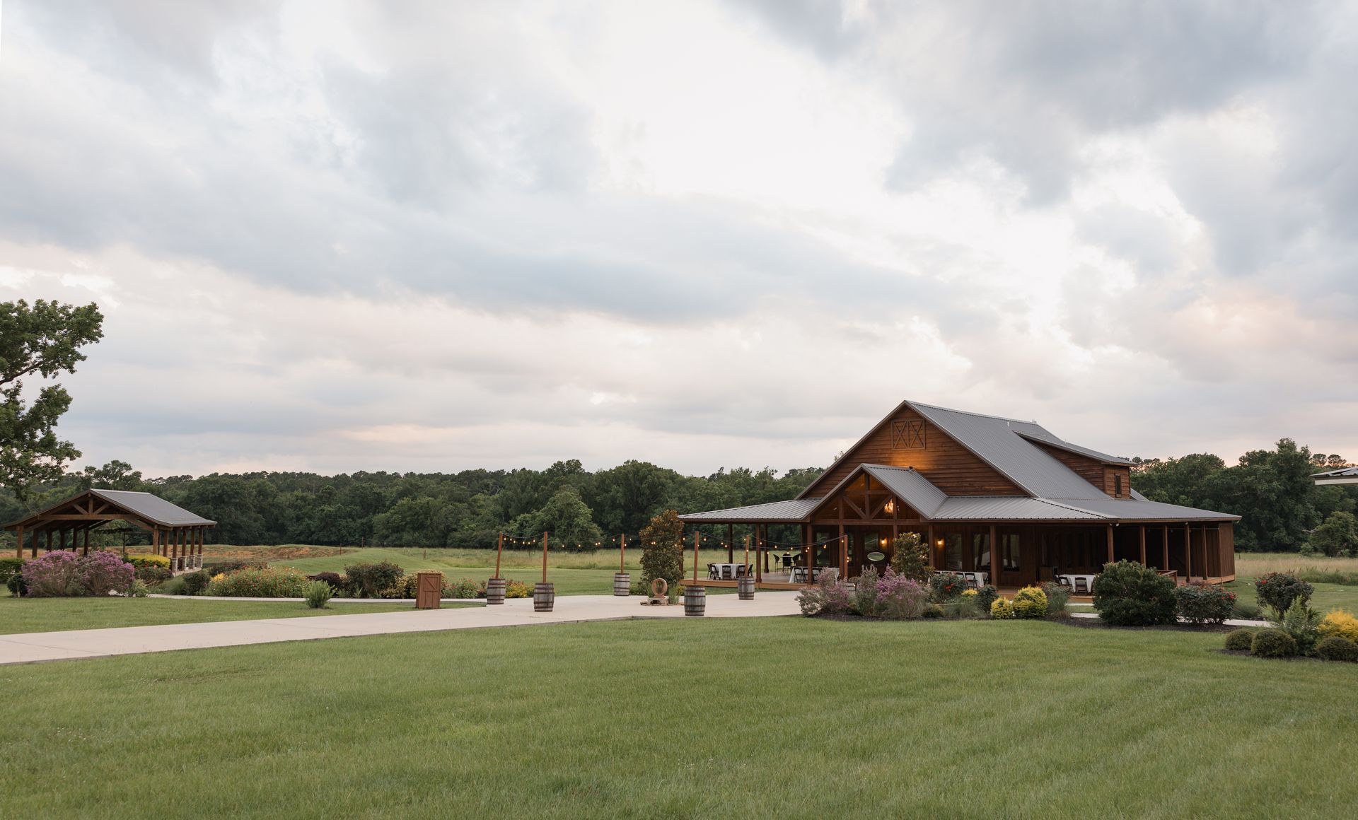 Rustic lodge with a wide green lawn under a cloudy sky, surrounded by trees and open grounds