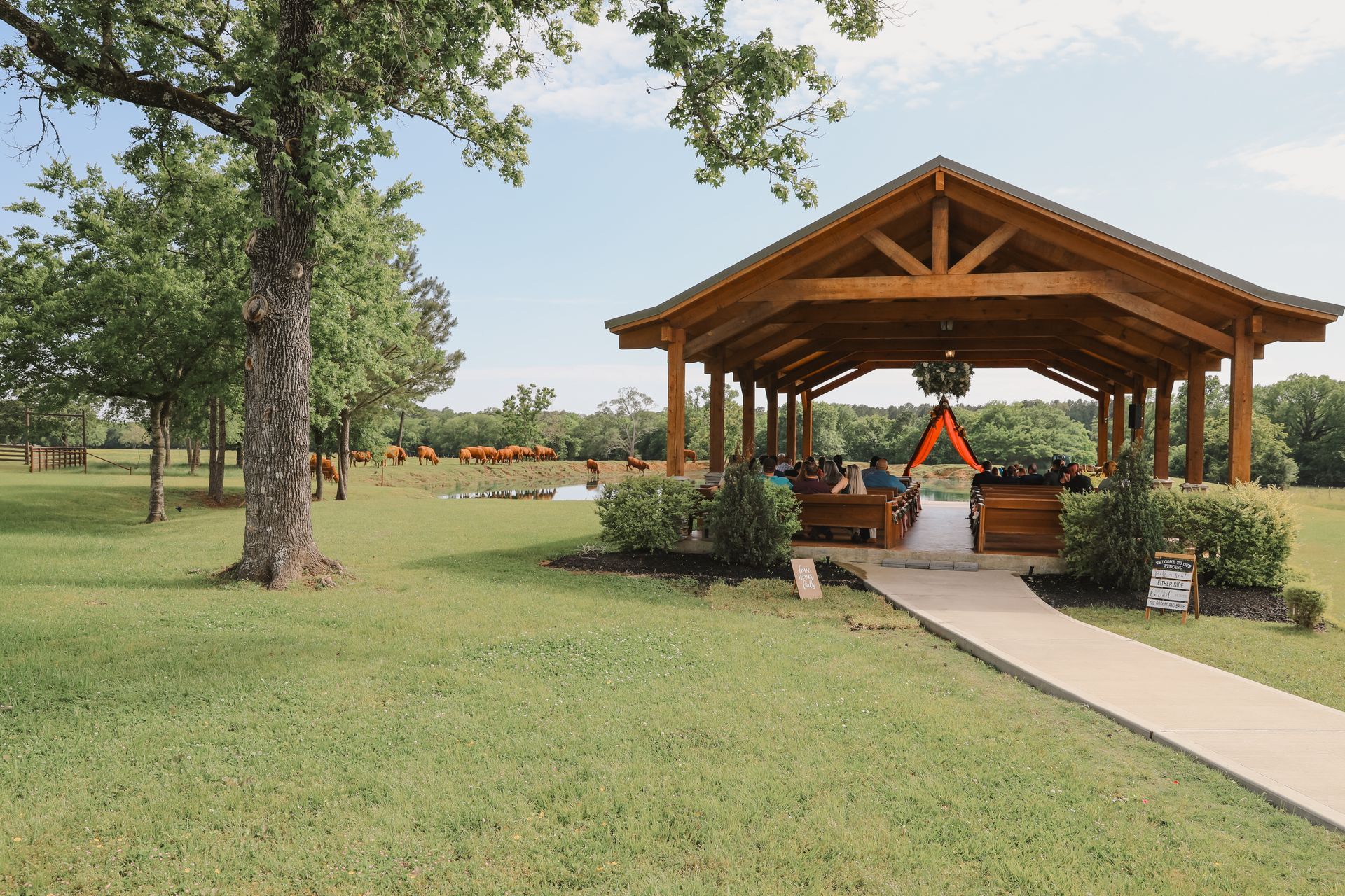 Wooden pavilion with a decorated altar in a grassy park, with a path leading to it.