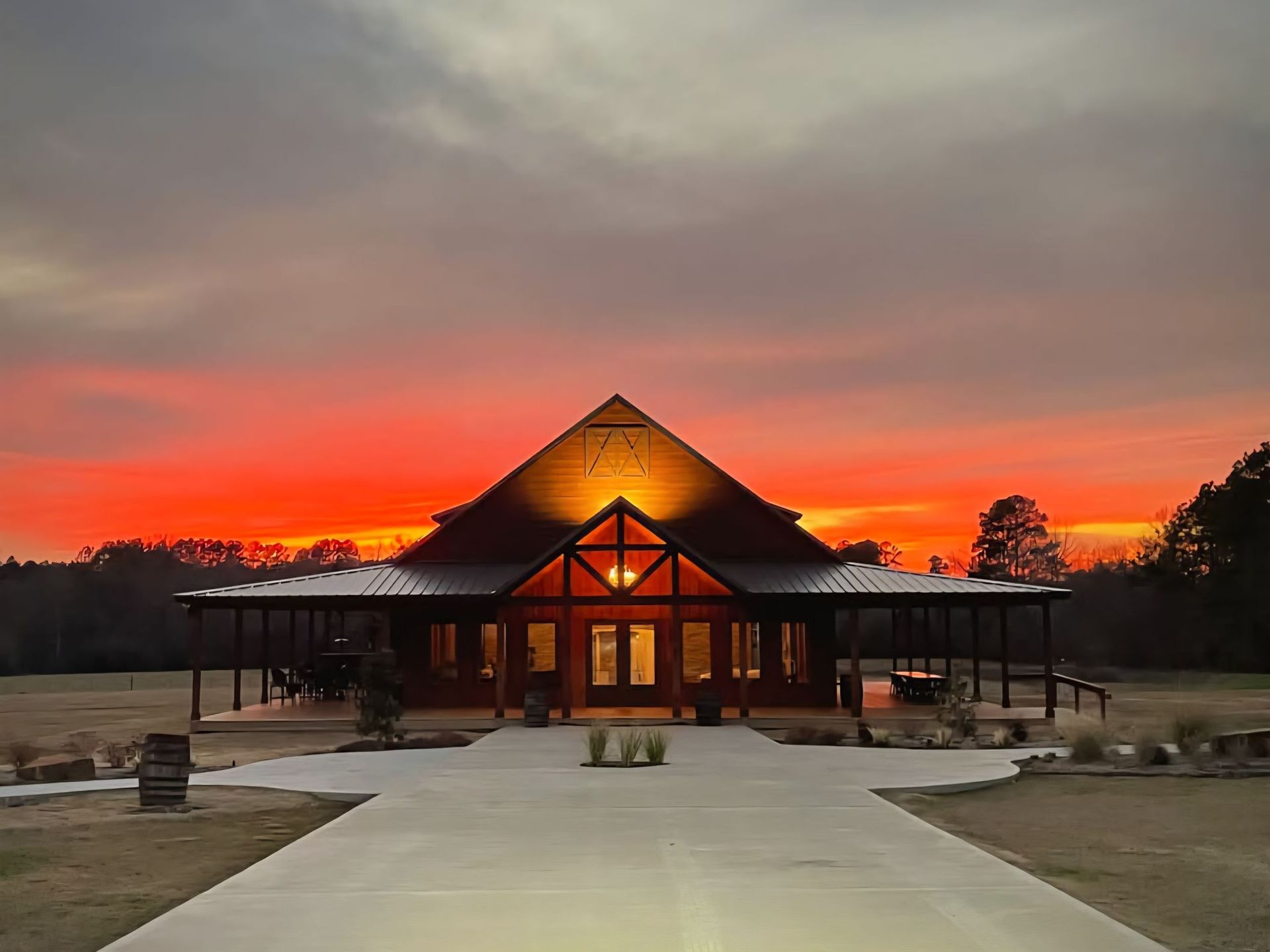 Front view of a pavilion at sunset with a glowing orange sky and long walkway