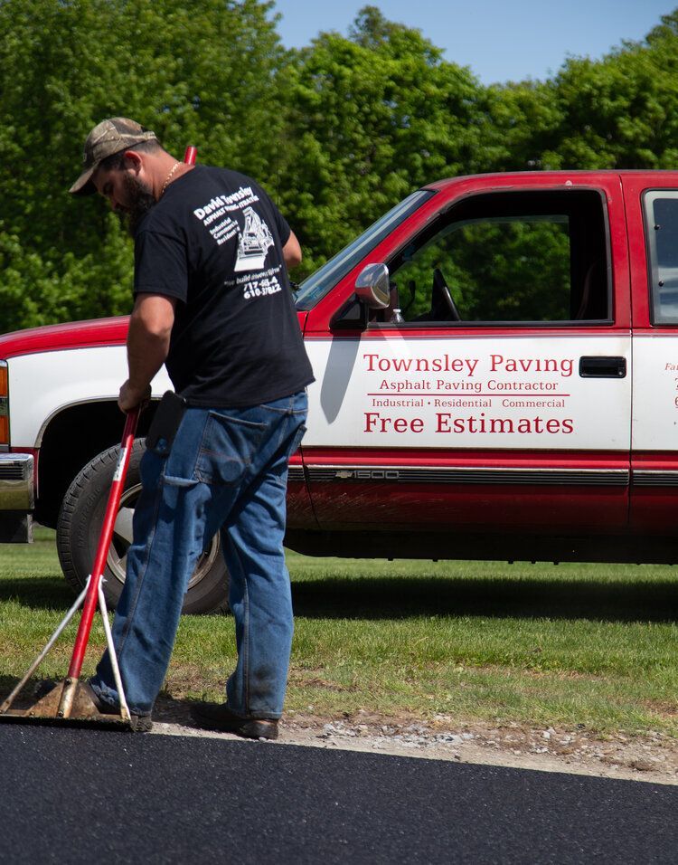 A man is standing in front of a townsley paving truck