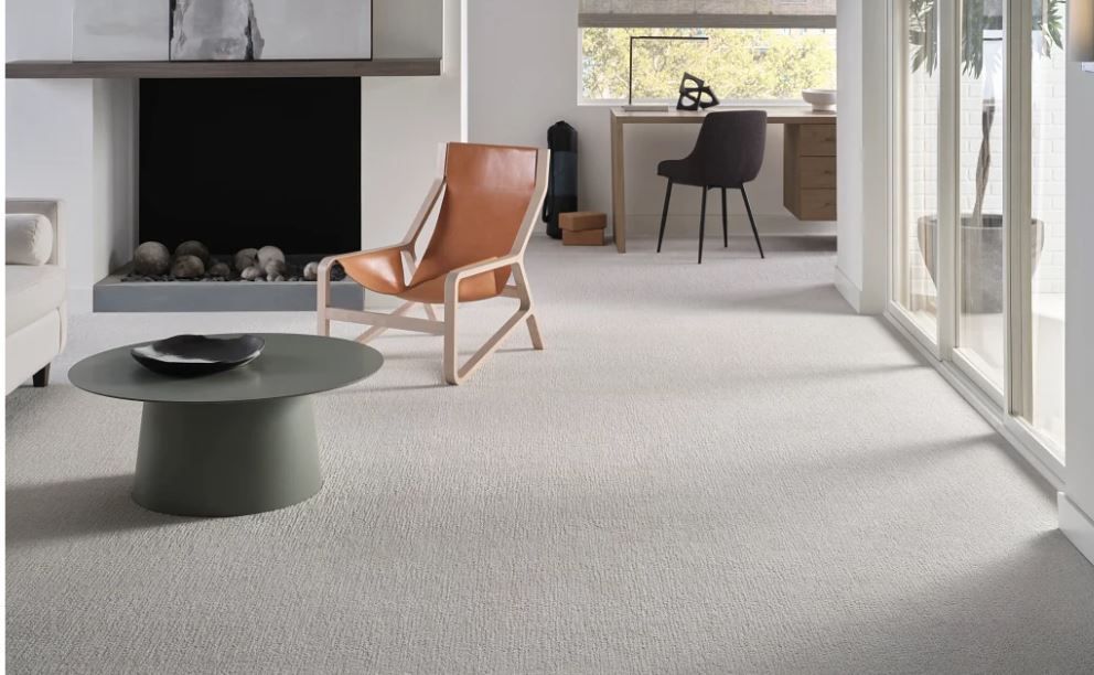 A living room with a fireplace, chair, coffee table, and desk.