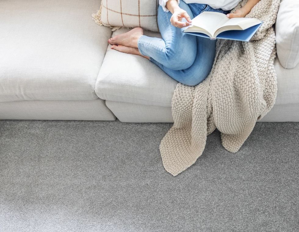 A woman is sitting on a couch reading a book.