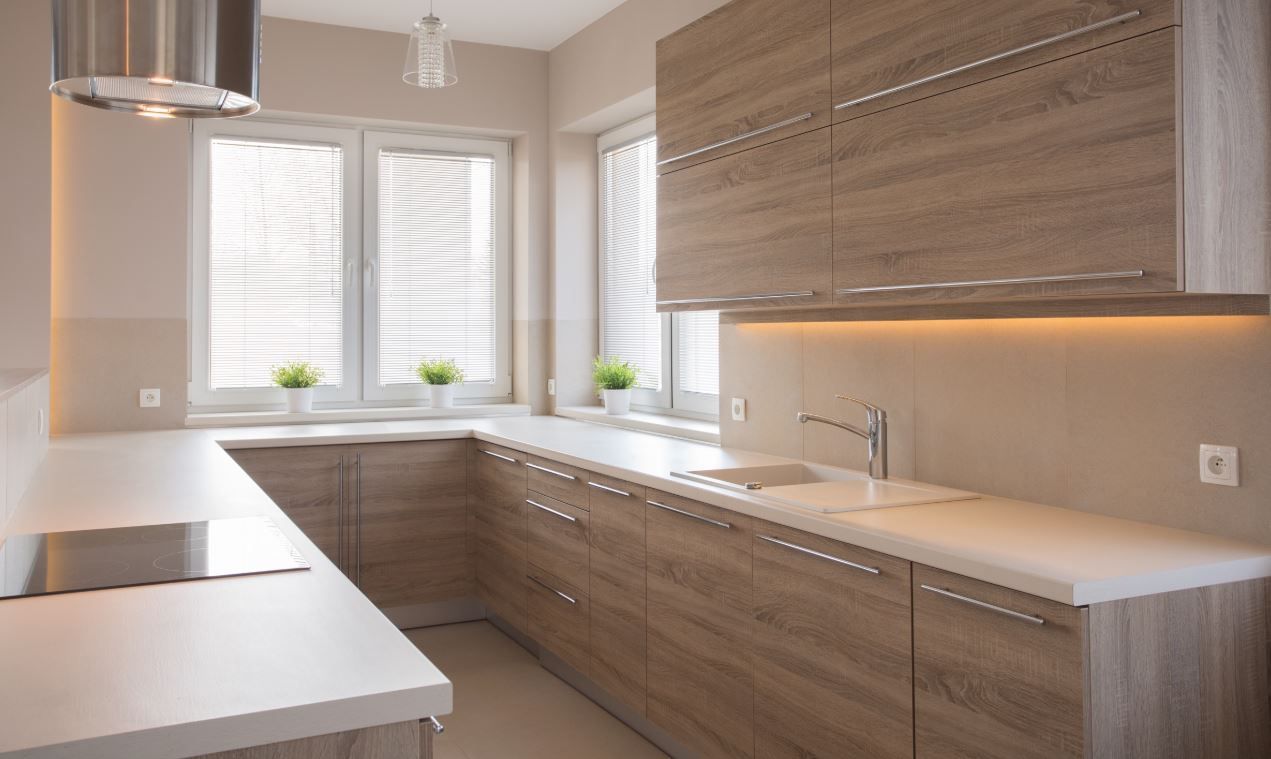 A kitchen with wooden cabinets and white counter tops.
