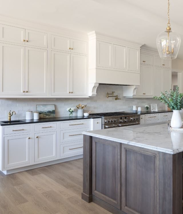 A kitchen with white cabinets, a stove, a sink, and a large island.