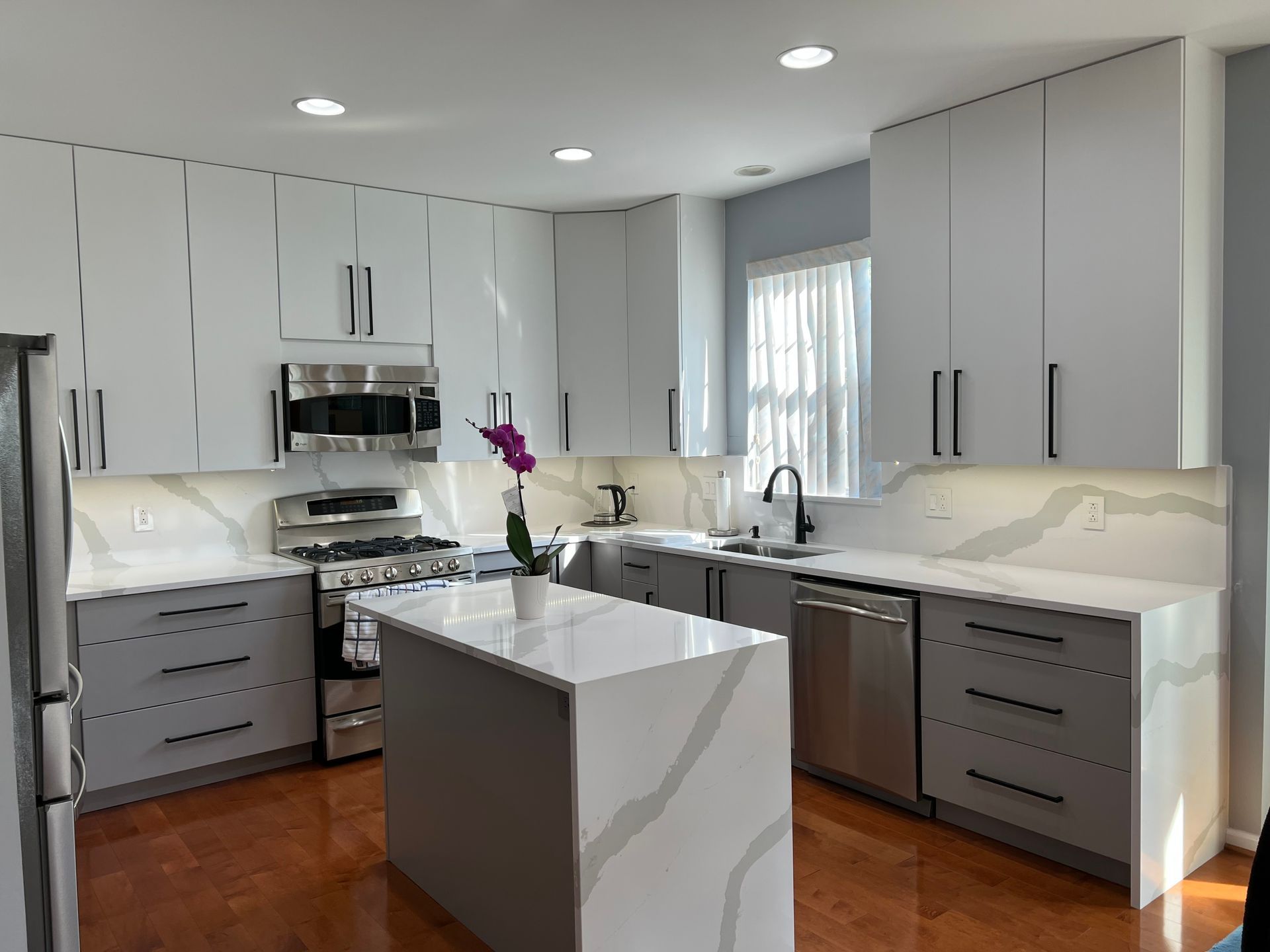 A kitchen with white cabinets, stainless steel appliances, and a large island.