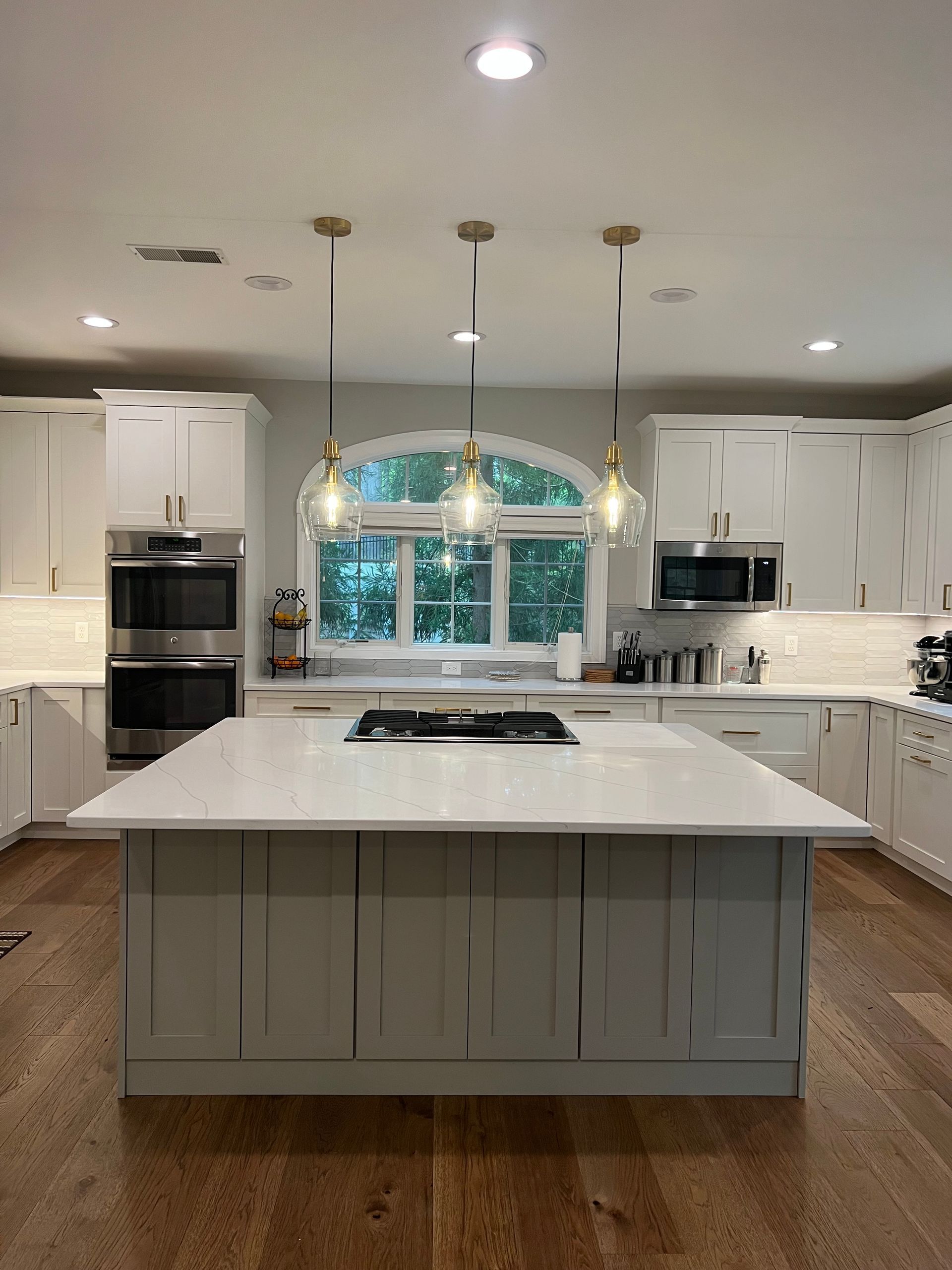 A kitchen with white cabinets, stainless steel appliances, and a large island.