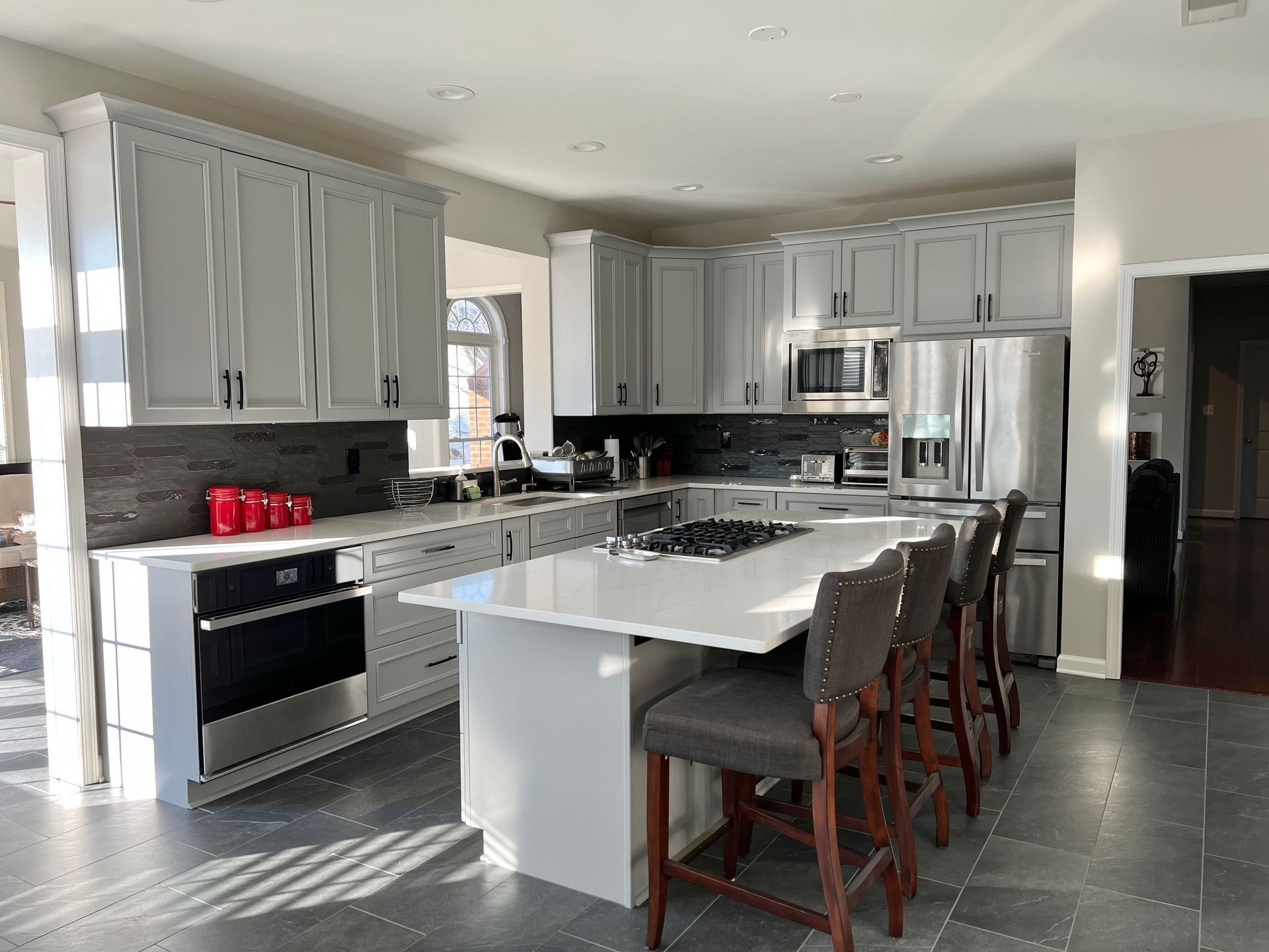 A kitchen with white cabinets, stainless steel appliances, and a large island.