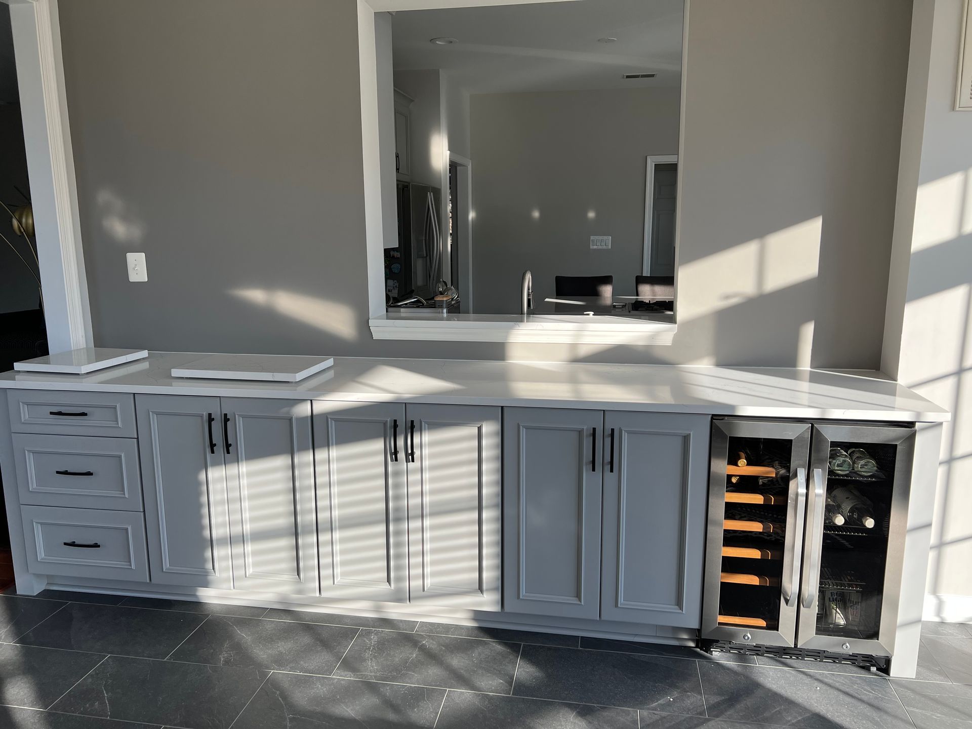 A kitchen with gray cabinets and a wine cooler.
