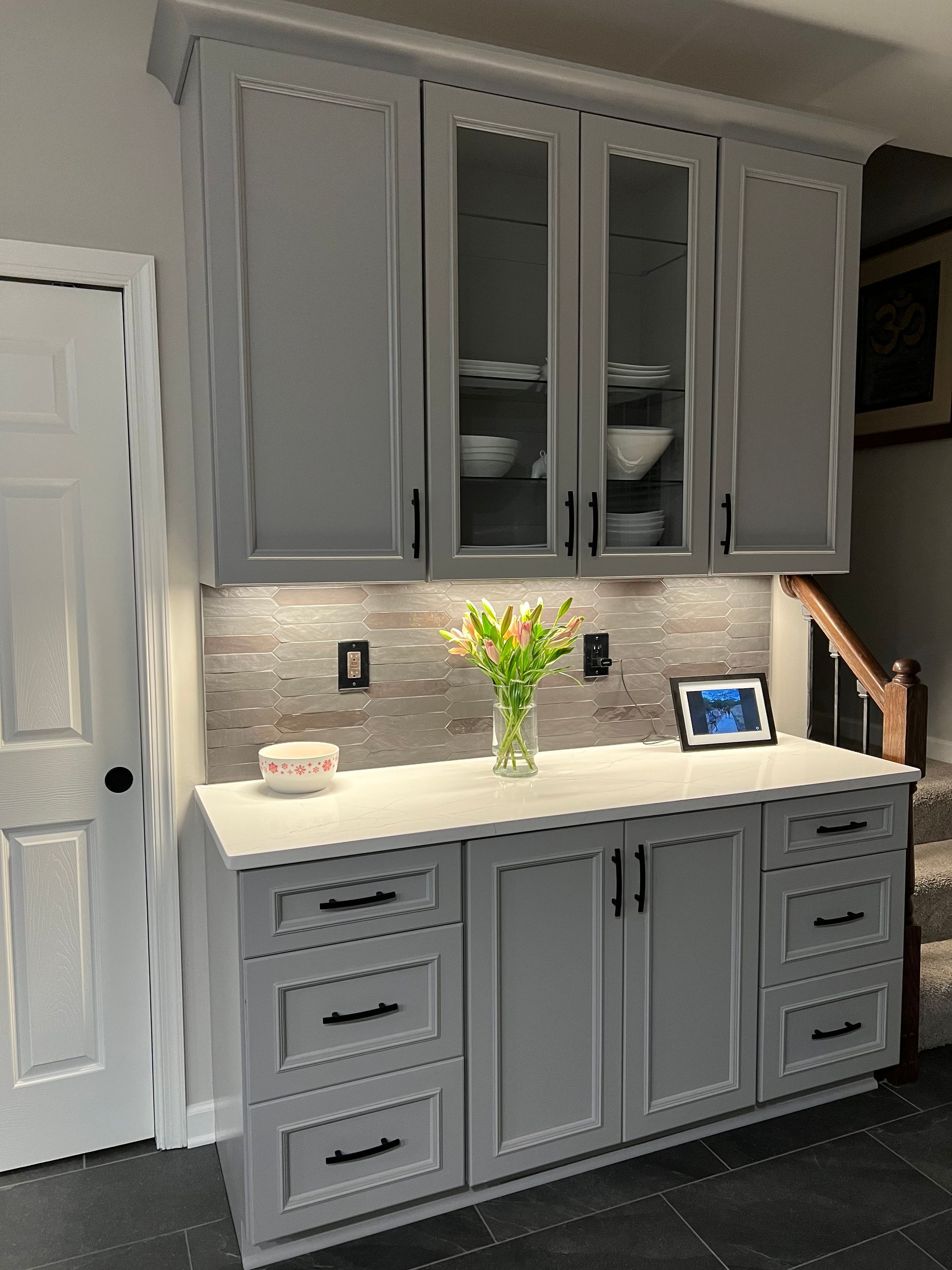 A kitchen with gray cabinets and white counter tops.