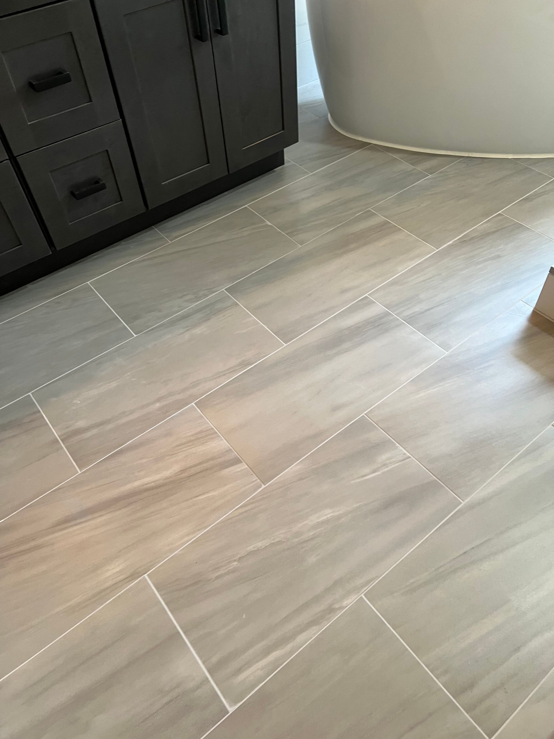 A bathroom floor with tiles that look like wood.