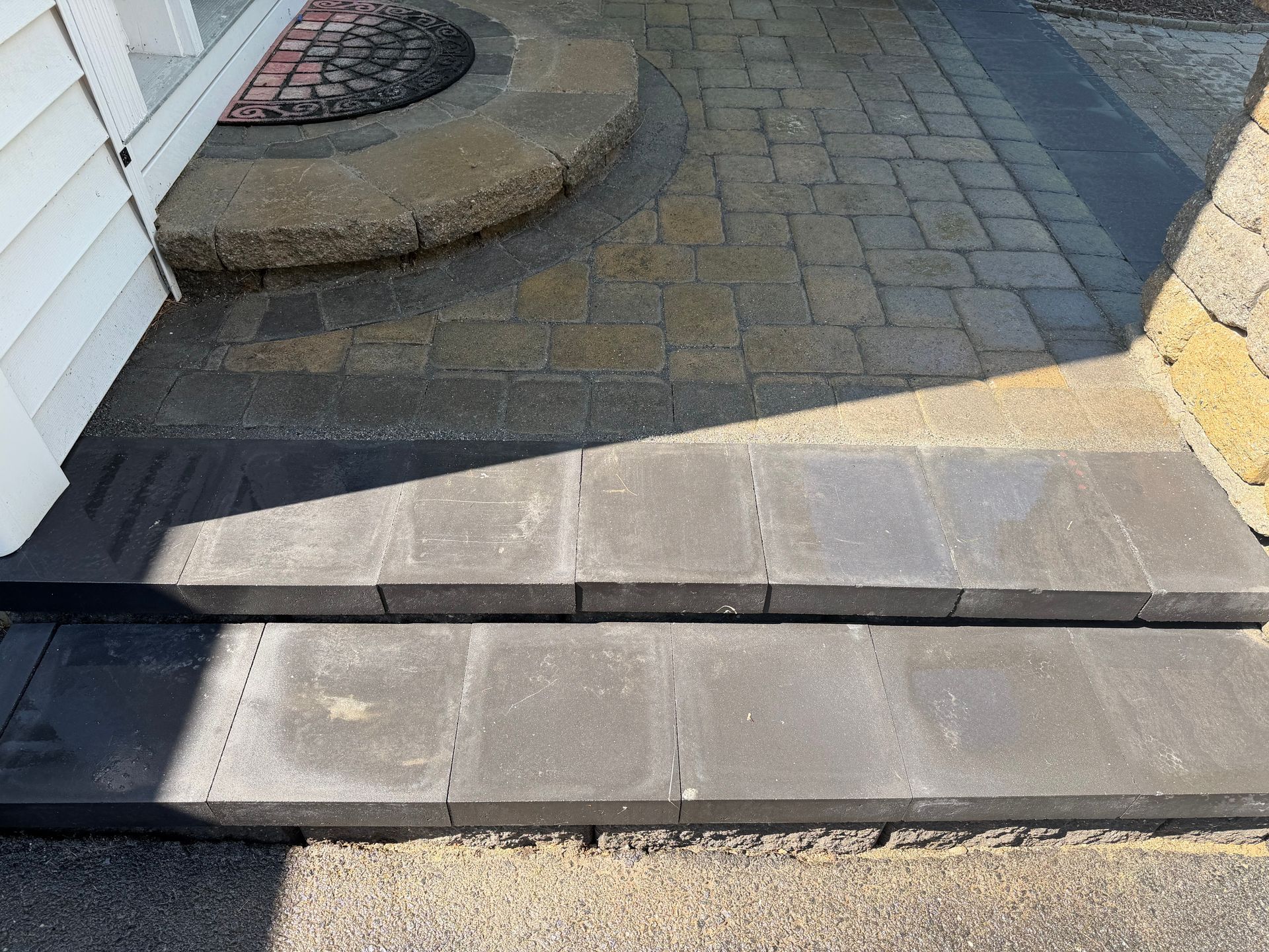 Stone walkway with a low step and curb beside a house entrance