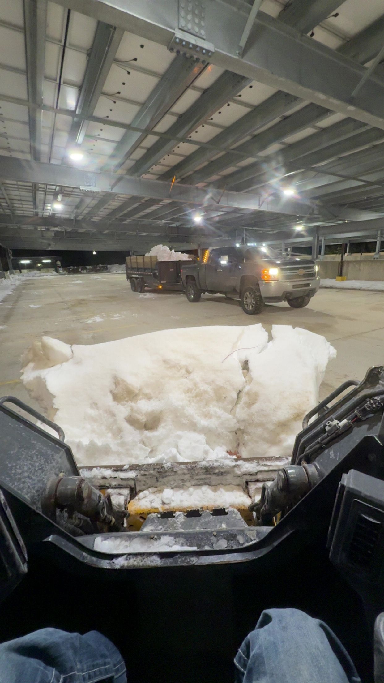 Snowy warehouse interior with a pickup truck driving past a snow pile, seen from inside another vehicle