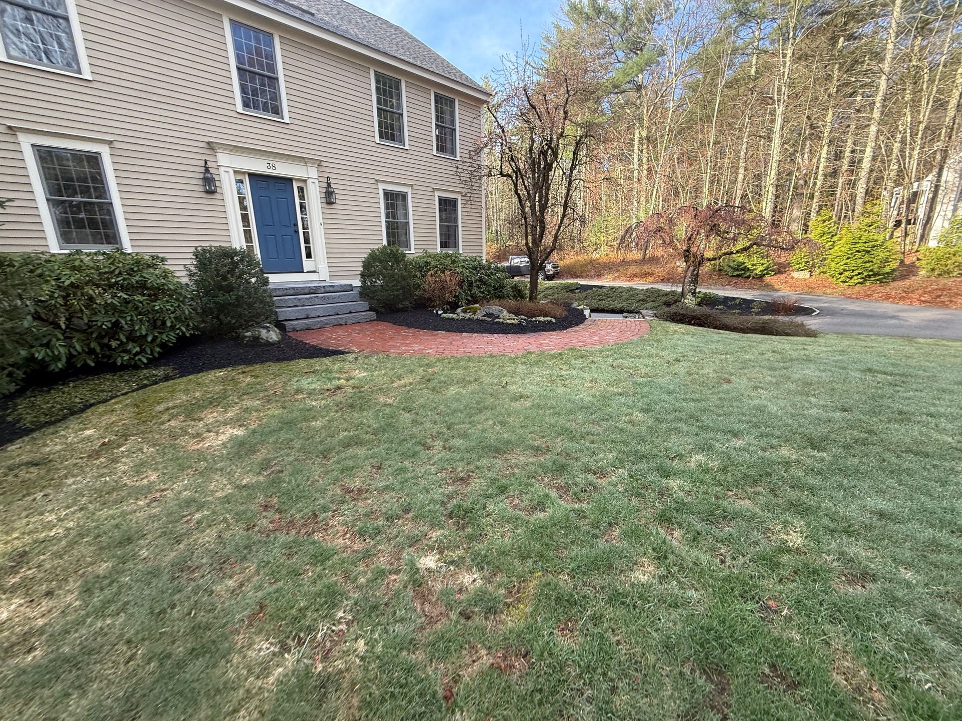 Suburban house with a green lawn, shrubs, and a landscaped mulch bed along the front yard