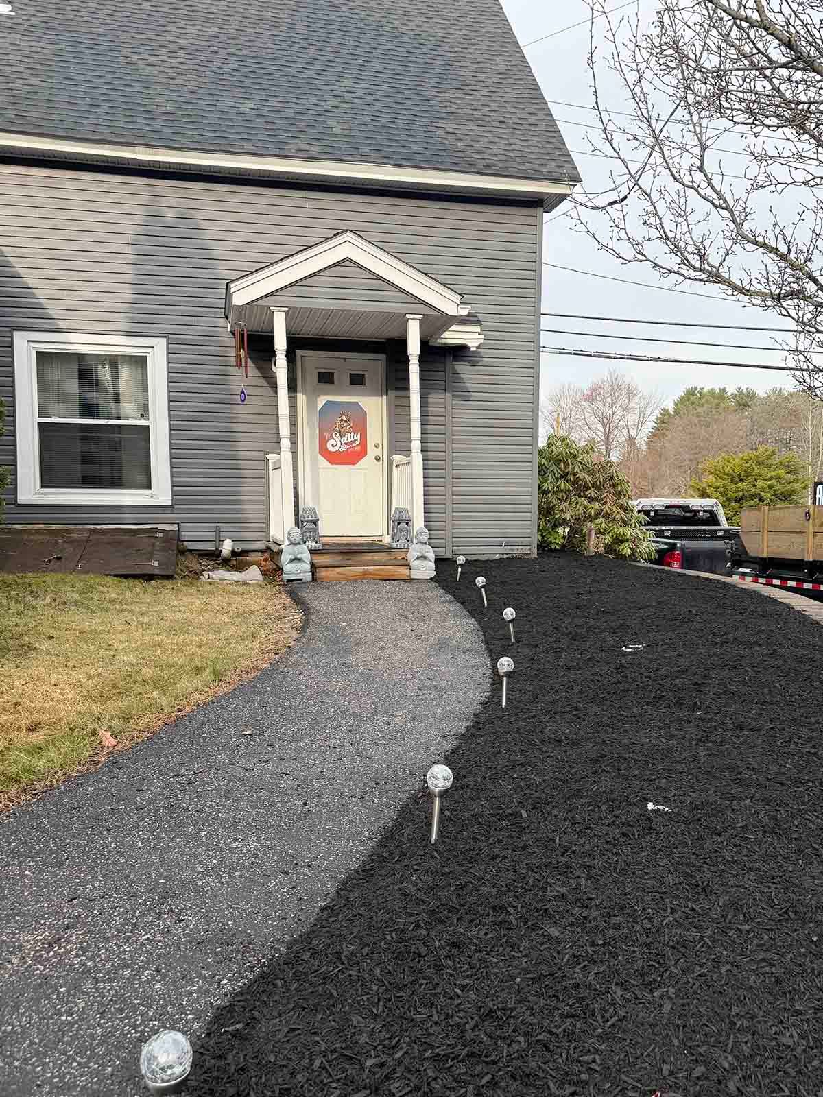 Front walkway with gravel path, porch steps, and Halloween decorations on a gray house