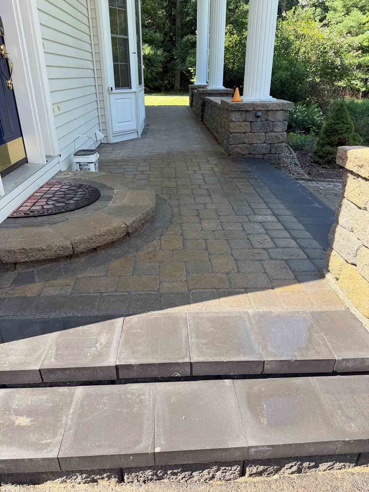Front porch with stone walkway, steps, white columns, and a house entrance