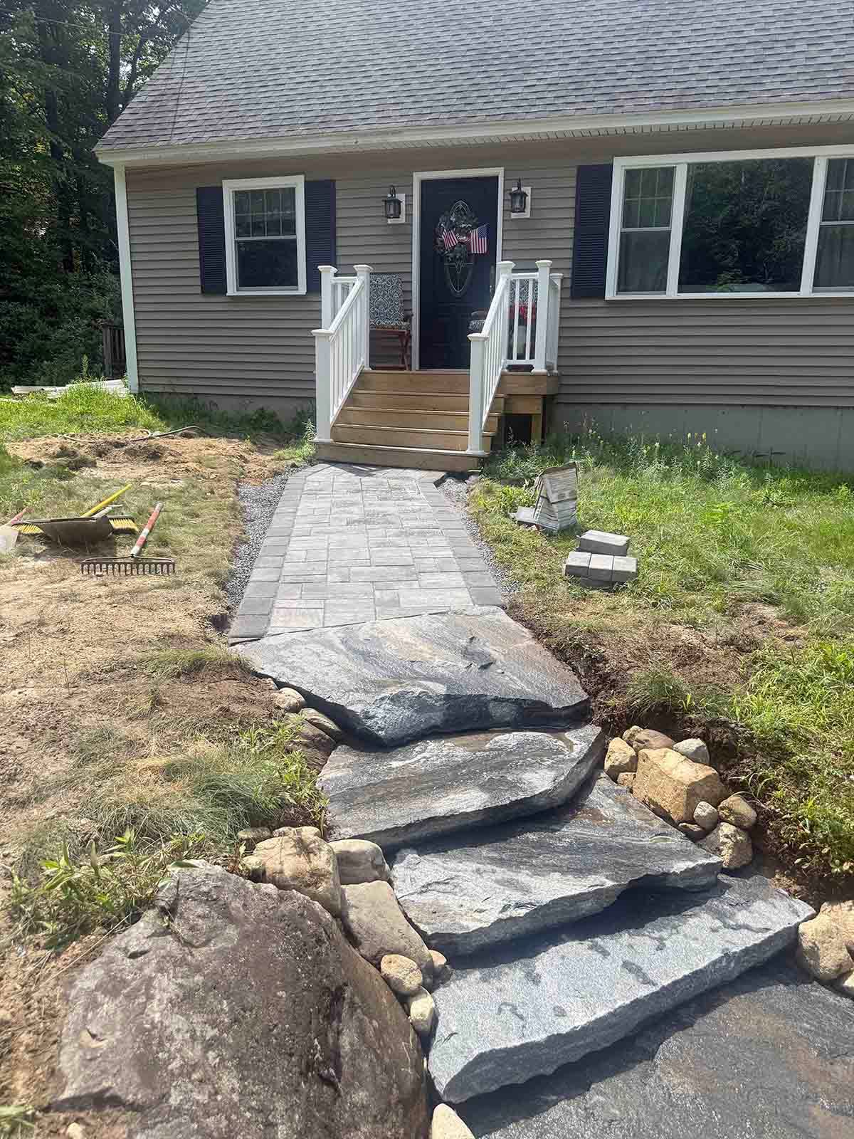 Front walkway with broken stone steps leading to a house entrance and porch.