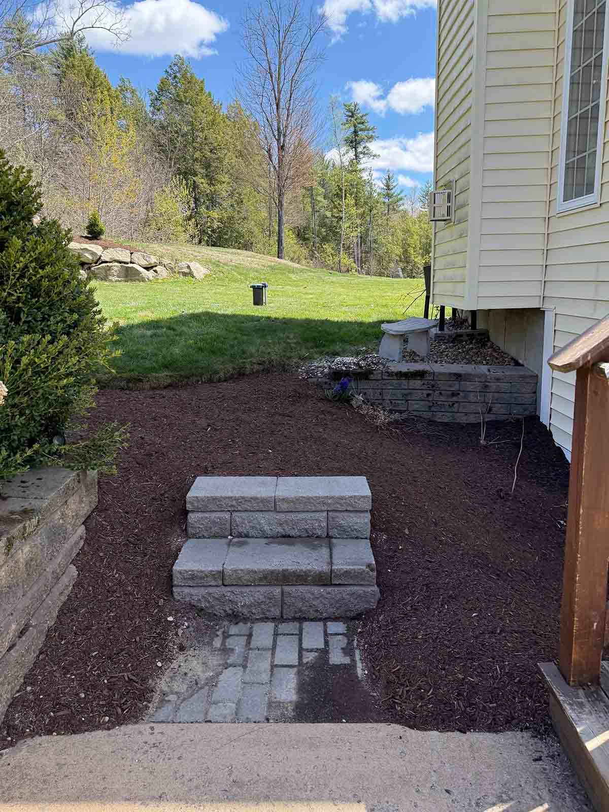 Backyard steps of stacked concrete blocks leading from a patio to a grassy yard beside a house